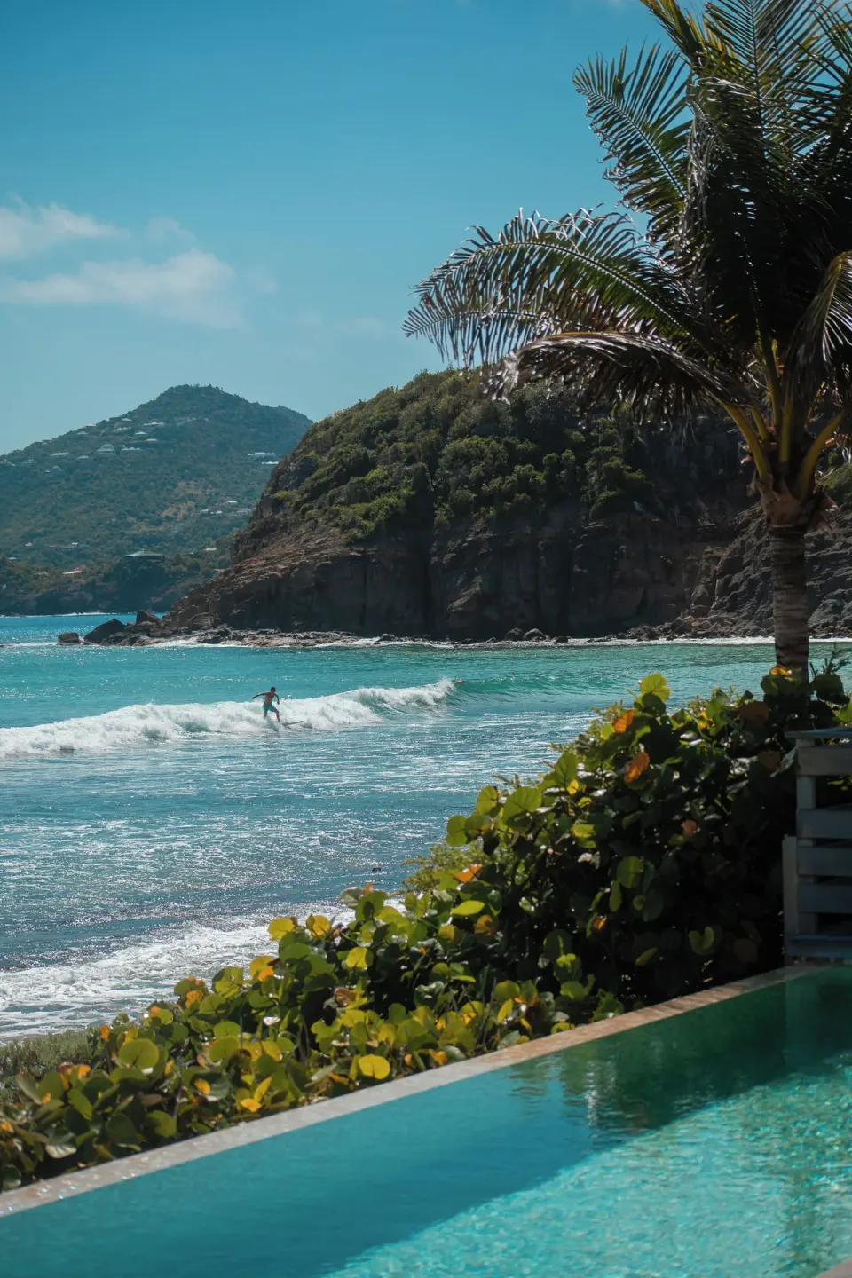 Infinity pool edge overlooking turquoise surf and a rocky headland at Hotel Manapany.
