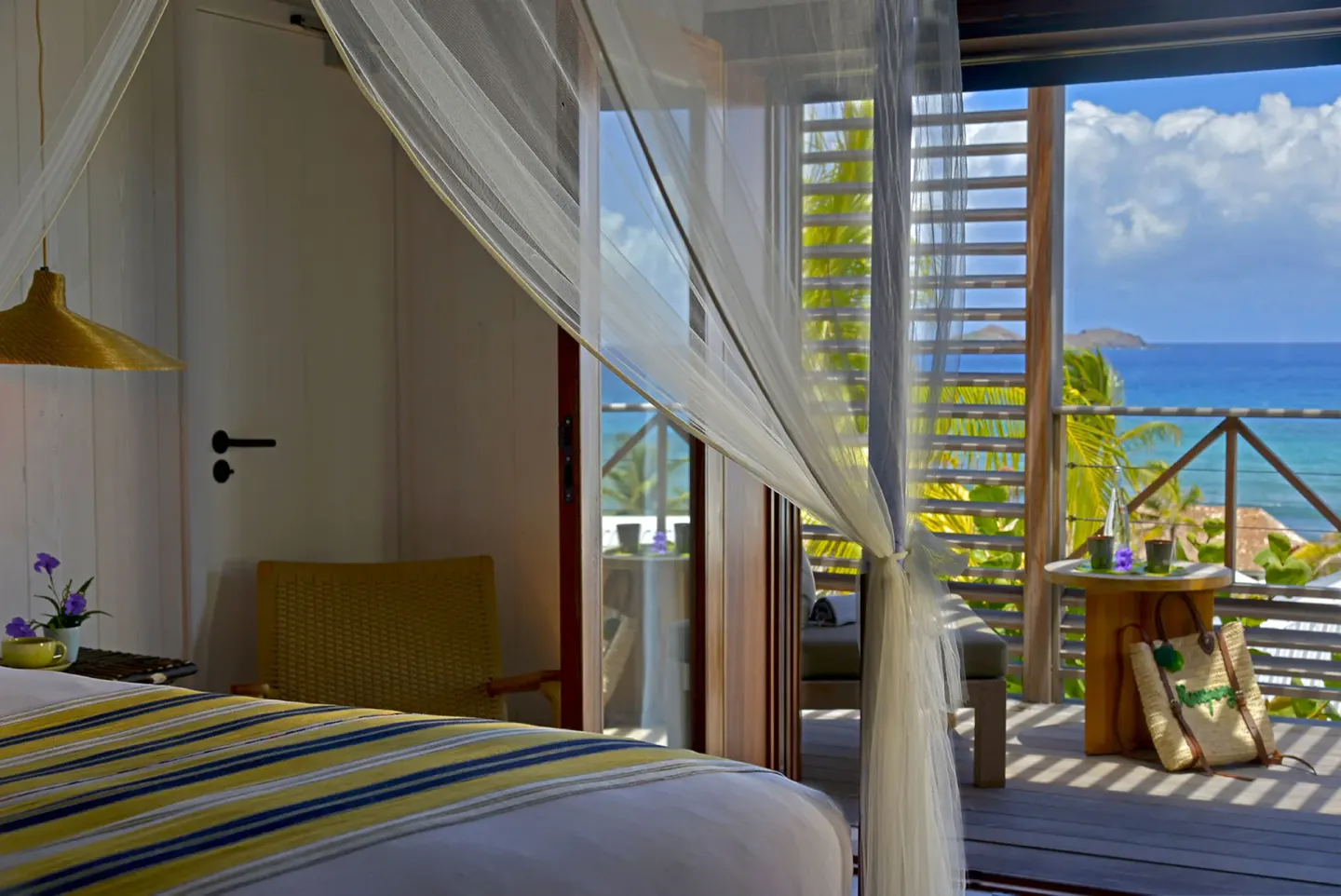 Guest room bed and balcony with ocean view at Hotel Manapany.