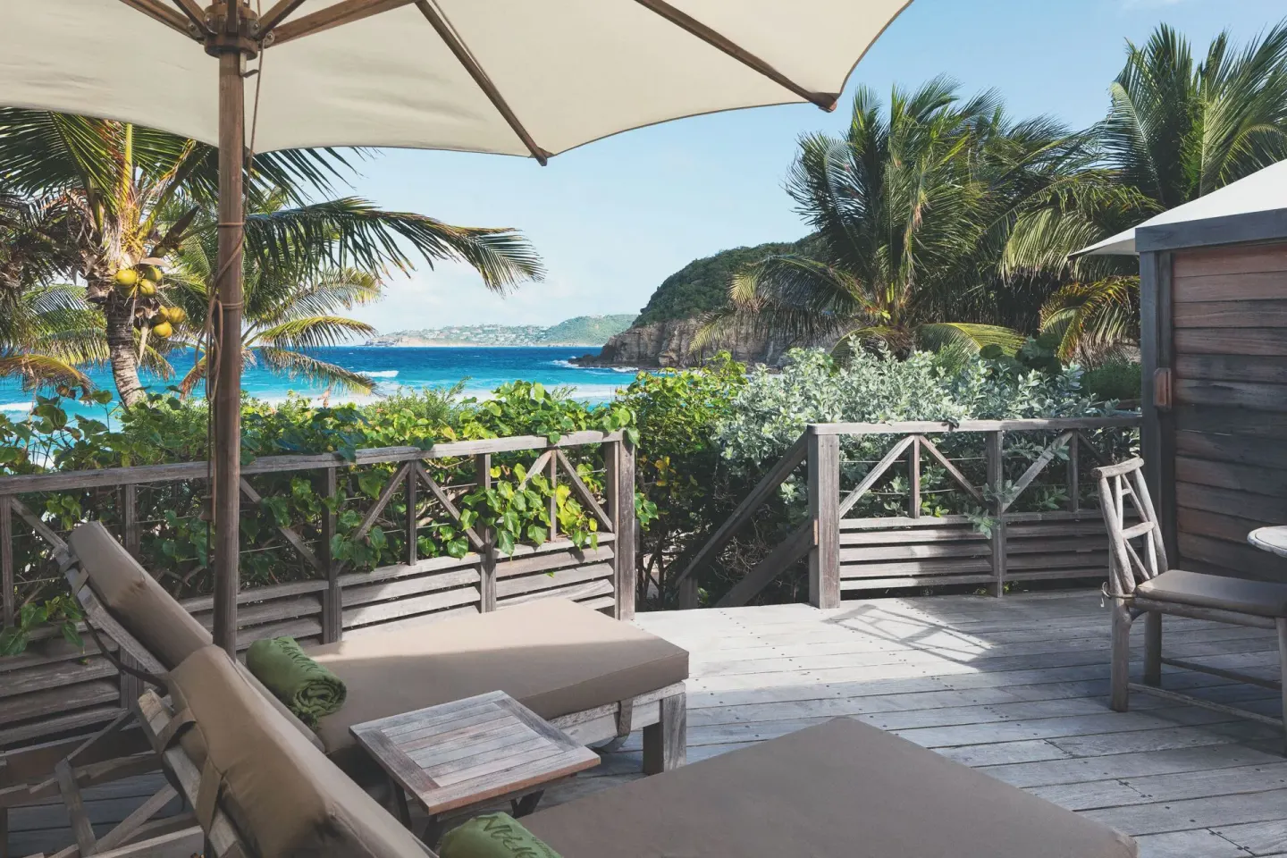Terrace loungers under an umbrella with ocean views at Hotel Manapany.