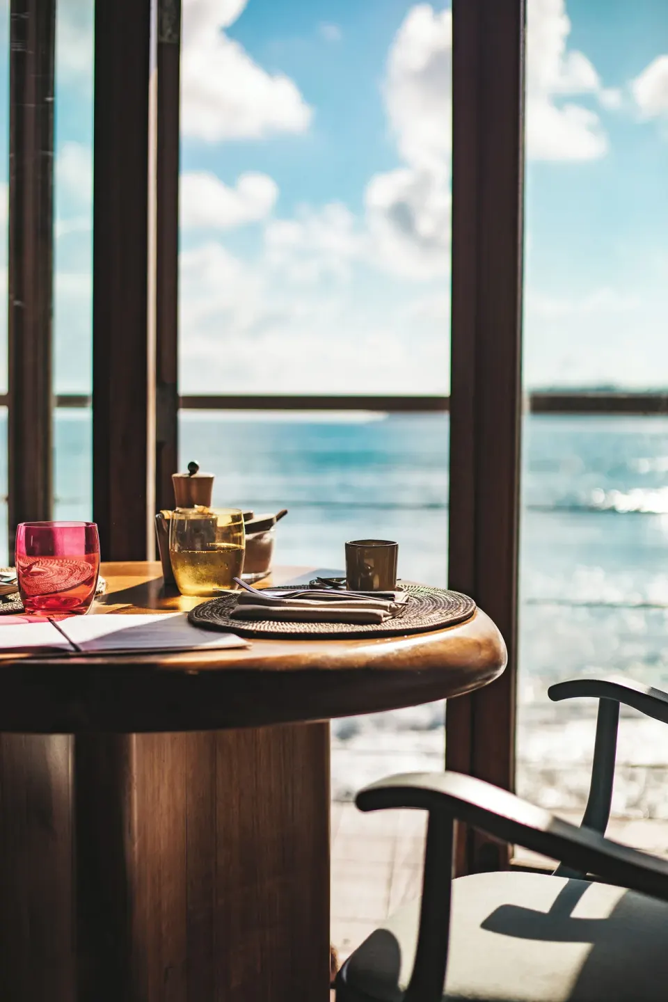 Table setting by tall windows overlooking the ocean at Hotel Manapany.