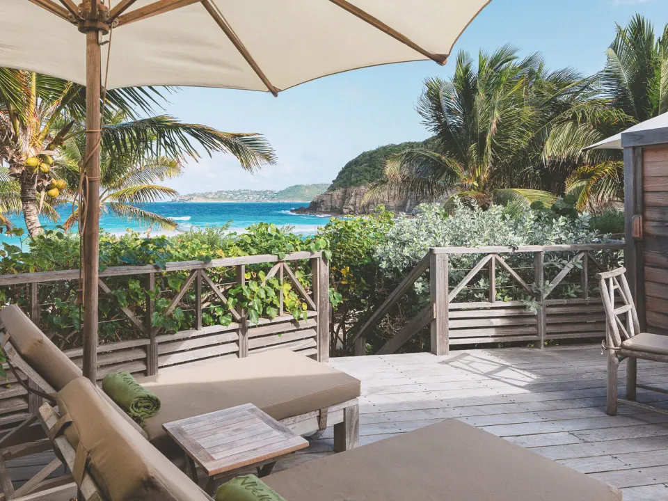 Junior Suite Beach View deck with loungers, umbrella, palms, and sea at Hotel Manapany.