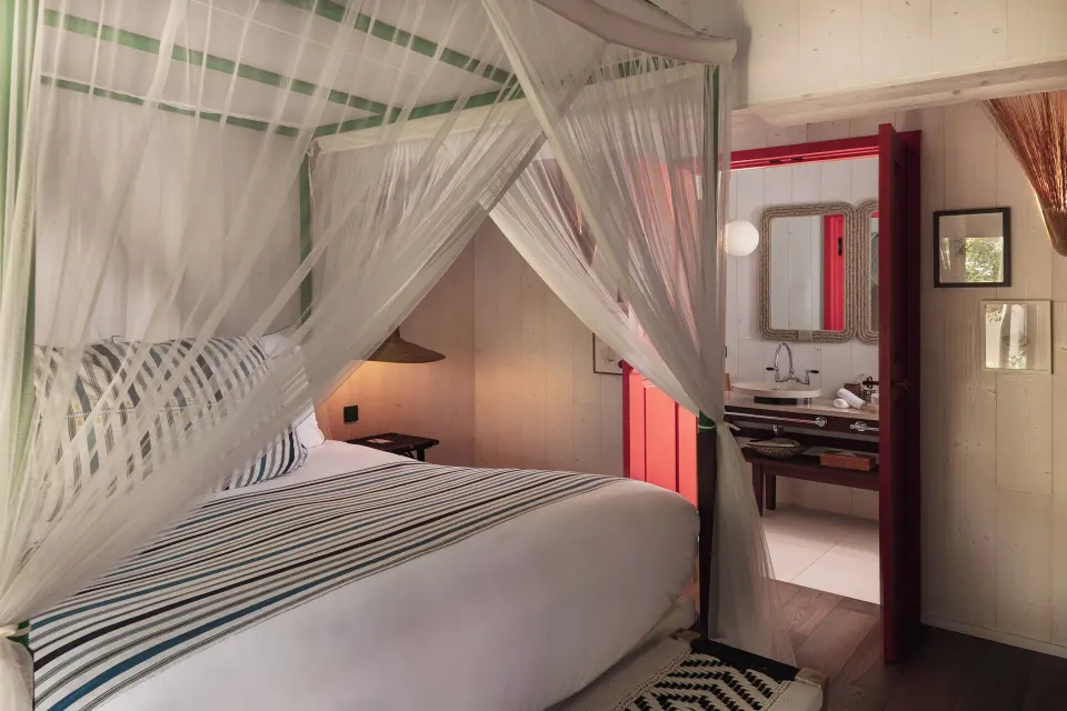 Junior Suite Beach View bedroom with canopy bed and bathroom vanity at Hotel Manapany.