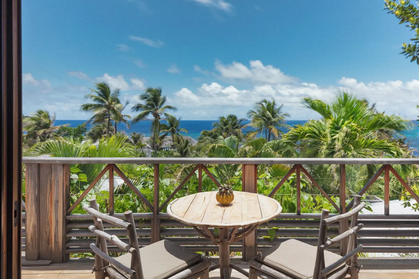 Junior Suite Ocean View balcony with table, chairs, palms and sea at Hotel Manapany.