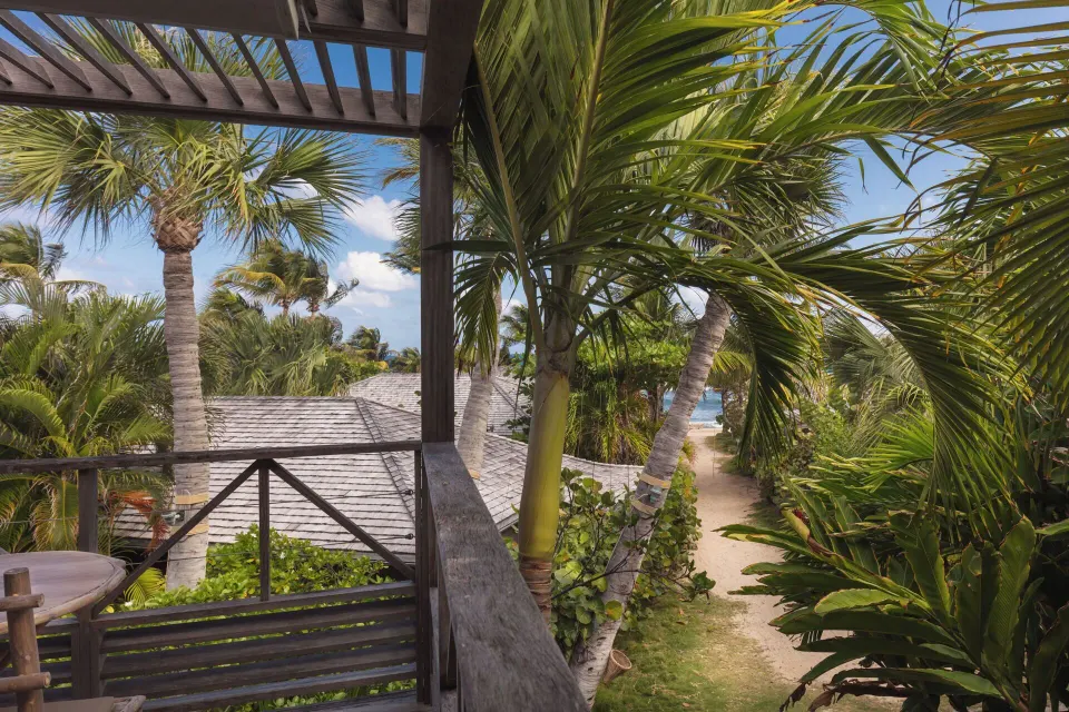 Garden View Room balcony overlooking palms, rooftops, and a sandy path at Hotel Manapany.