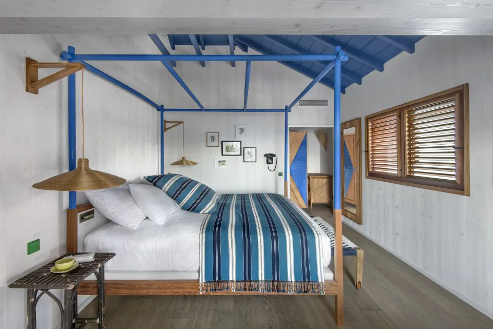 Garden View Room with blue four-poster bed and shutters at Hotel Manapany.