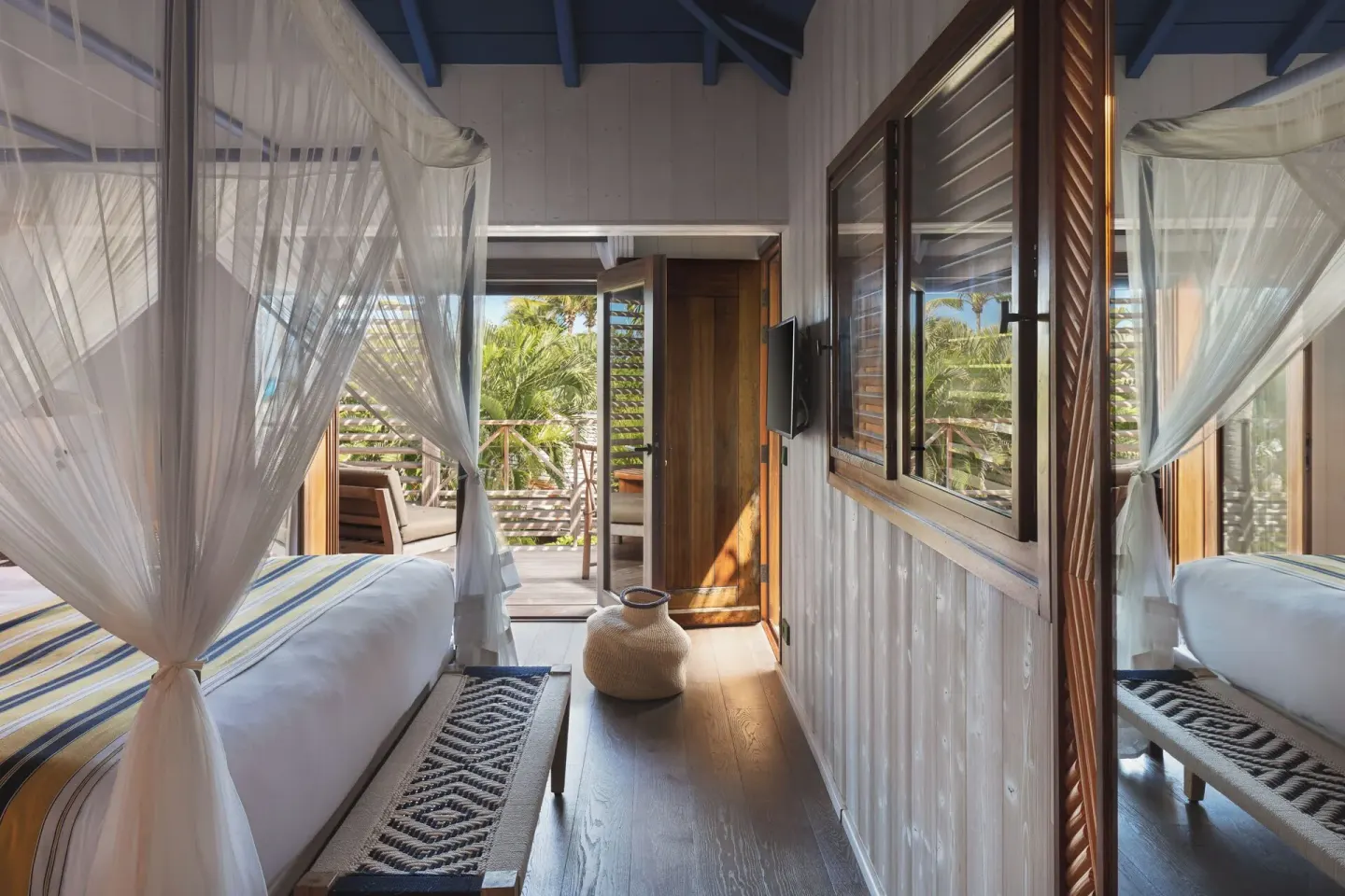 Garden View Room with netted bed, bench, mirror, and balcony door at Hotel Manapany.