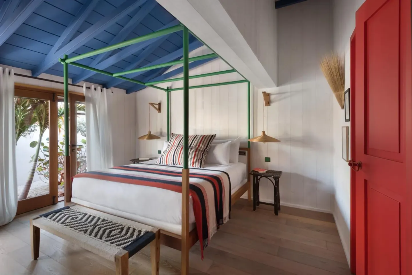Tropical Room bed with green canopy frame and blue ceiling at Hotel Manapany.