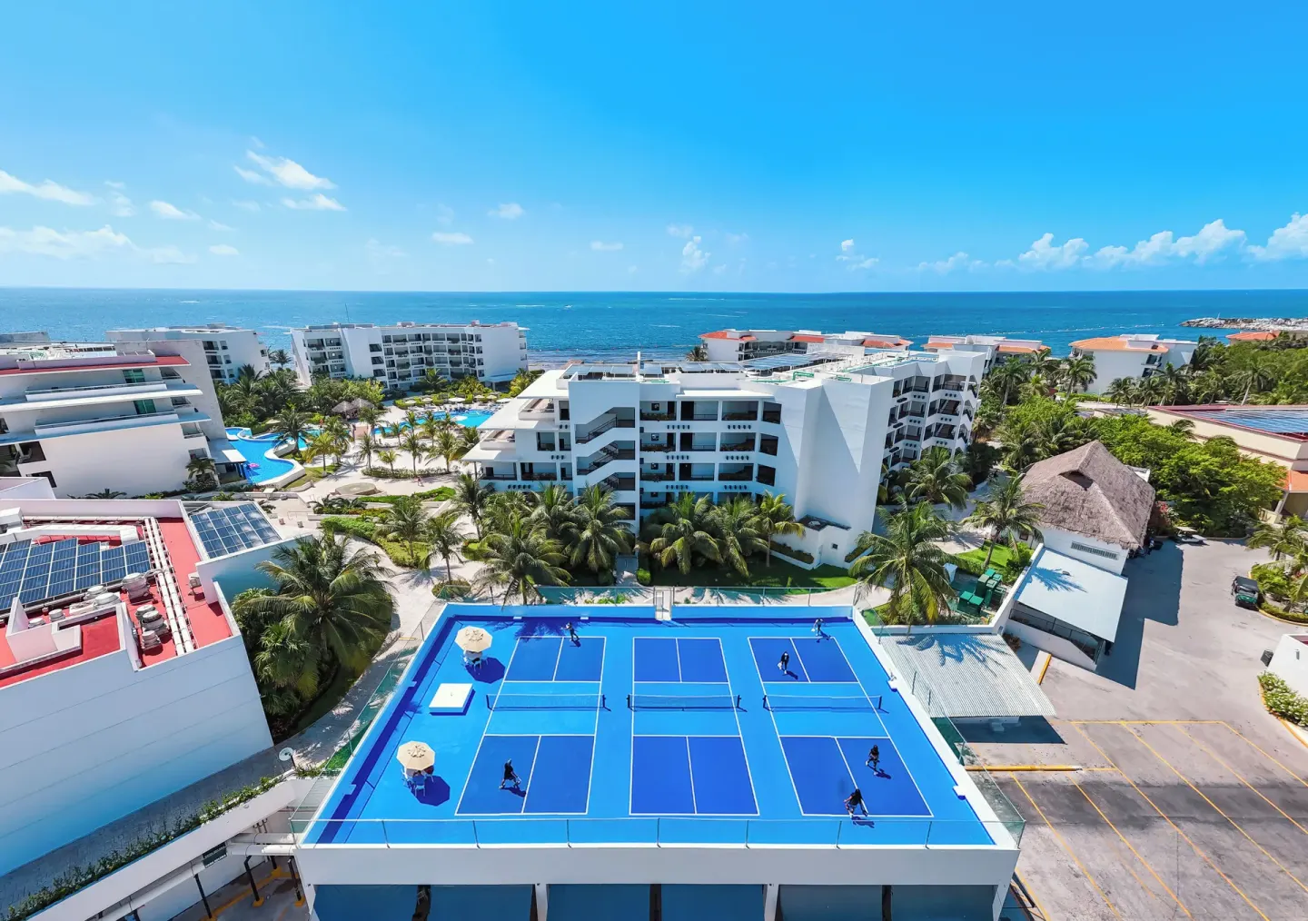 Aerial view of blue sports courts and resort buildings at Hotel Marina El Cid Spa & Beach Resort.