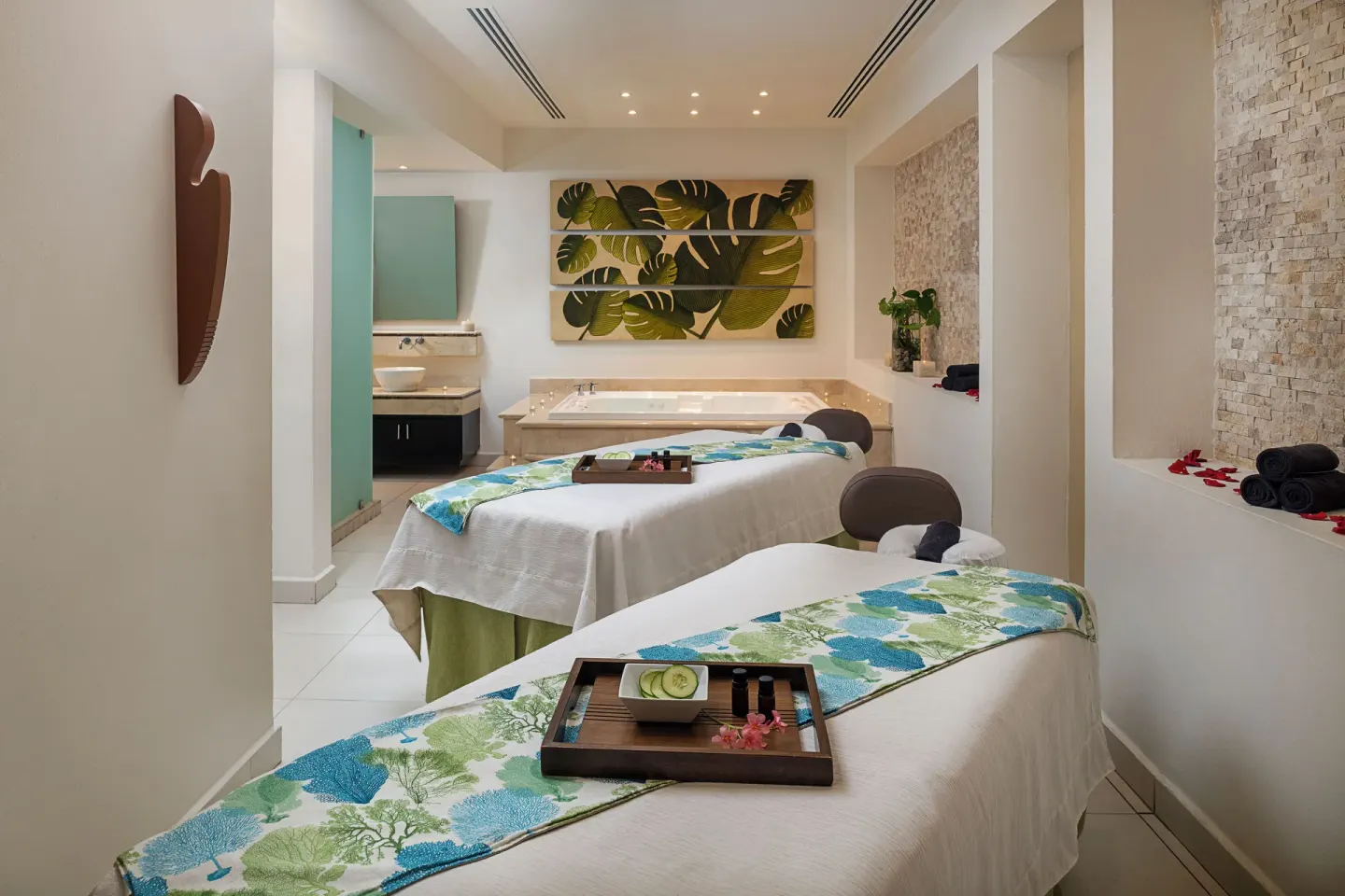 A spa treatment room with two massage tables and a soaking tub at Hotel Marina El Cid Spa & Beach Resort.