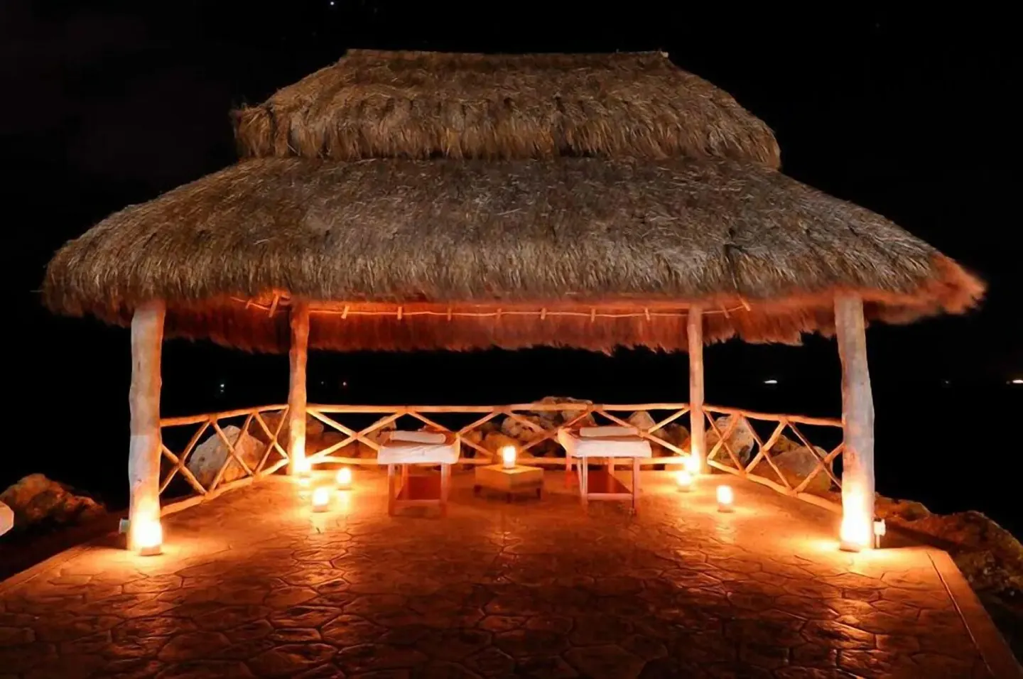 Thatched seaside massage palapa lit at night at Hotel Marina El Cid Spa & Beach Resort.