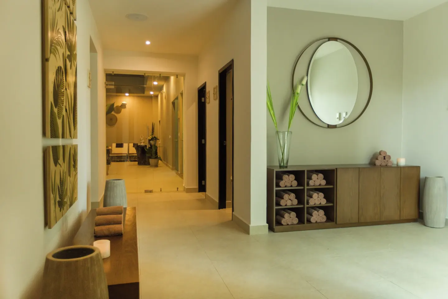 A spa corridor with towels, candles, and a round mirror at Hotel Marina El Cid Spa & Beach Resort.