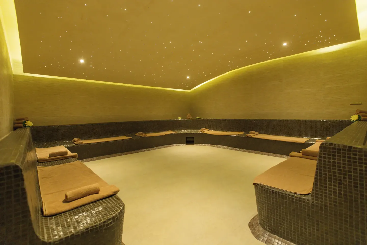 Dim spa relaxation room with tiled loungers at Hotel Marina El Cid Spa & Beach Resort.