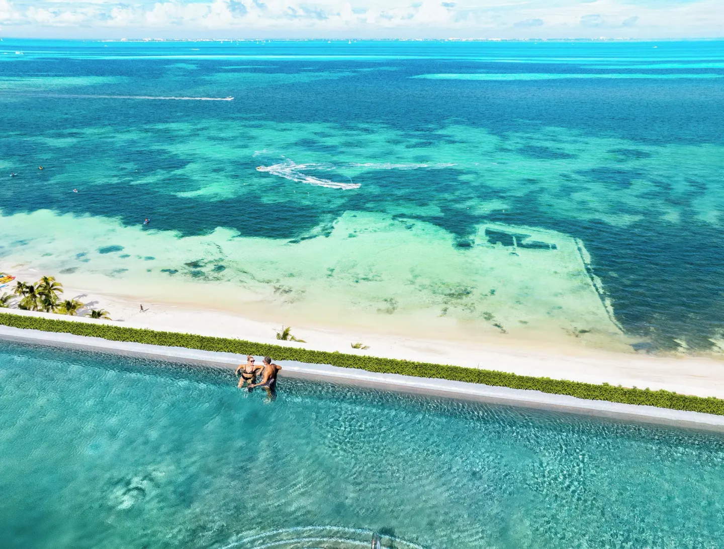 Aerial view of infinity pool above the beach and Caribbean at Hotel Mousai Cancun.