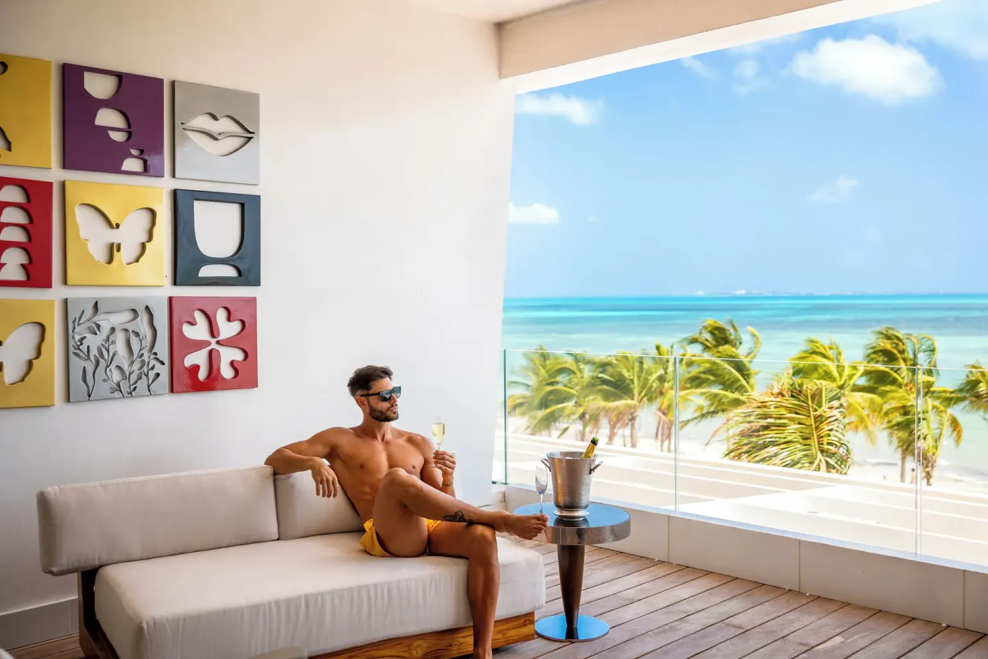 Guest on a balcony sofa with beach and ocean view at Hotel Mousai Cancun.