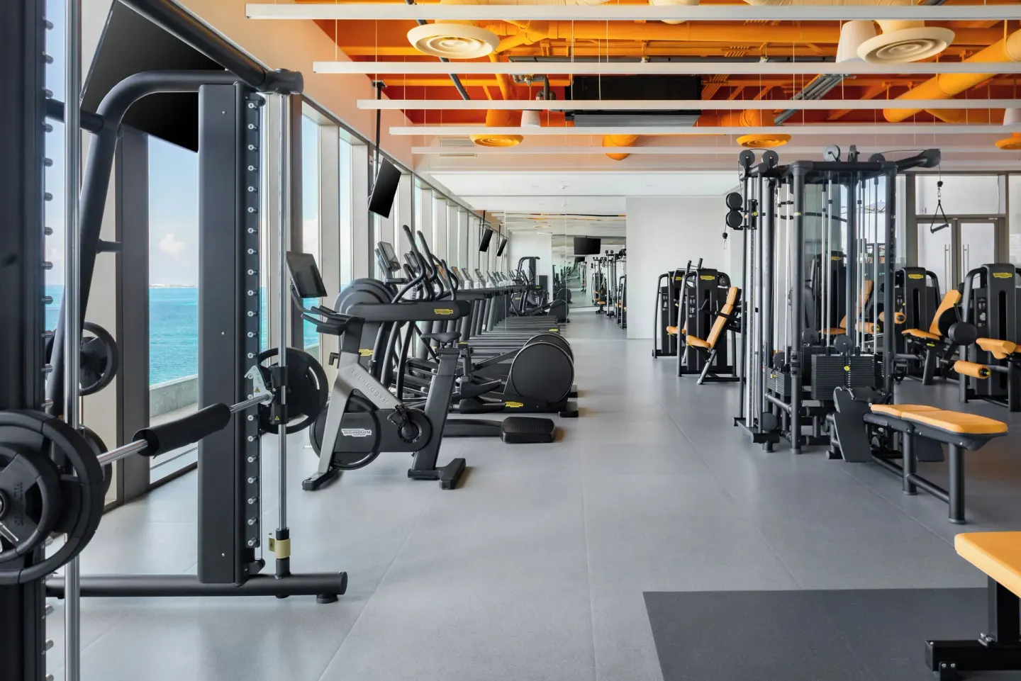 Fitness center with cardio and weight machines facing the sea at Hotel Mousai Cancun.
