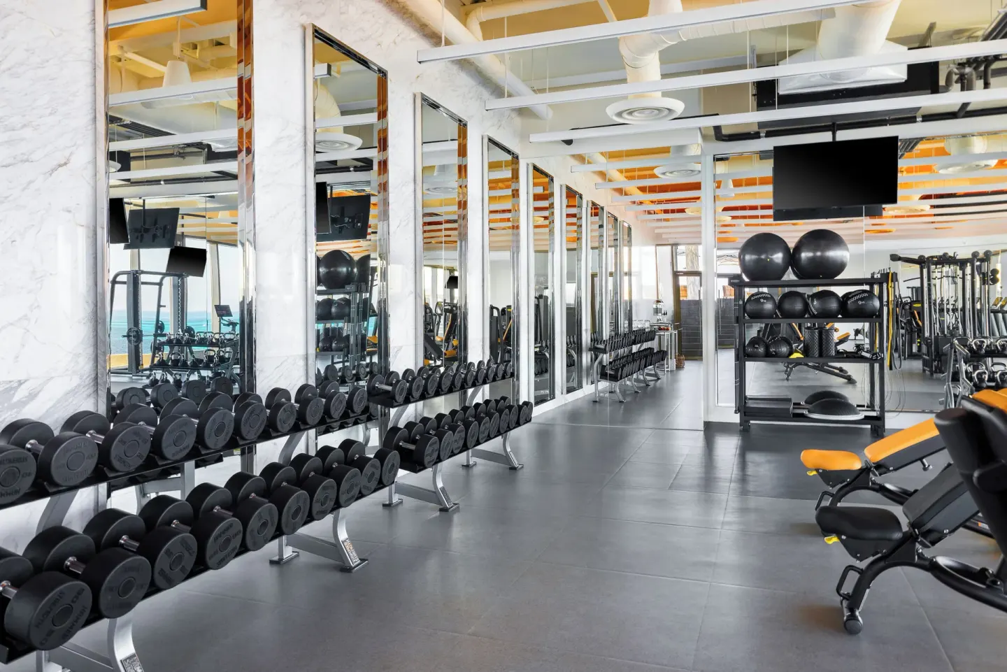 Fitness center dumbbell racks and mirrors at Hotel Mousai Cancun.