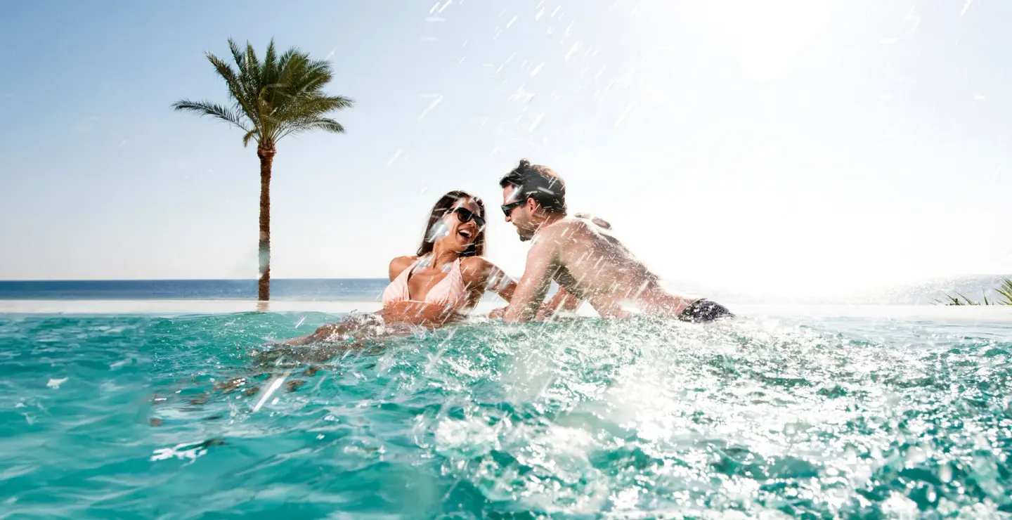 Couple splashing in an infinity pool at Hotel Mousai Cancun.