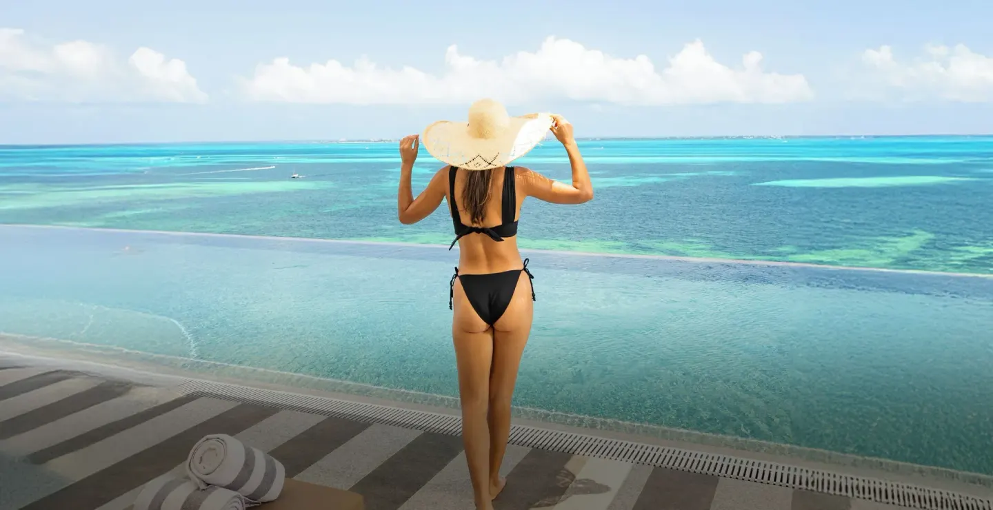 Woman in a sun hat standing by the infinity pool at Hotel Mousai Cancun.