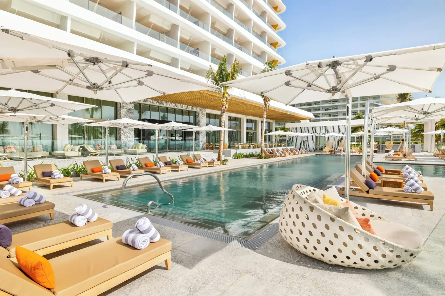 Main pool with loungers, umbrellas and resort building at Hotel Mousai Cancun.