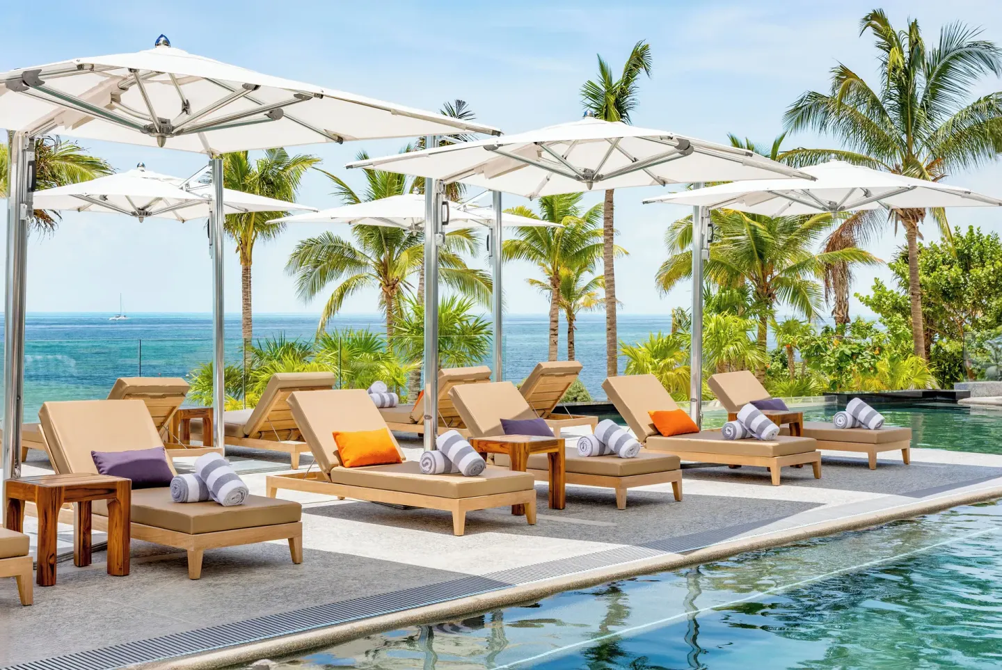 Poolside loungers and white umbrellas by the Caribbean at Hotel Mousai Cancun.