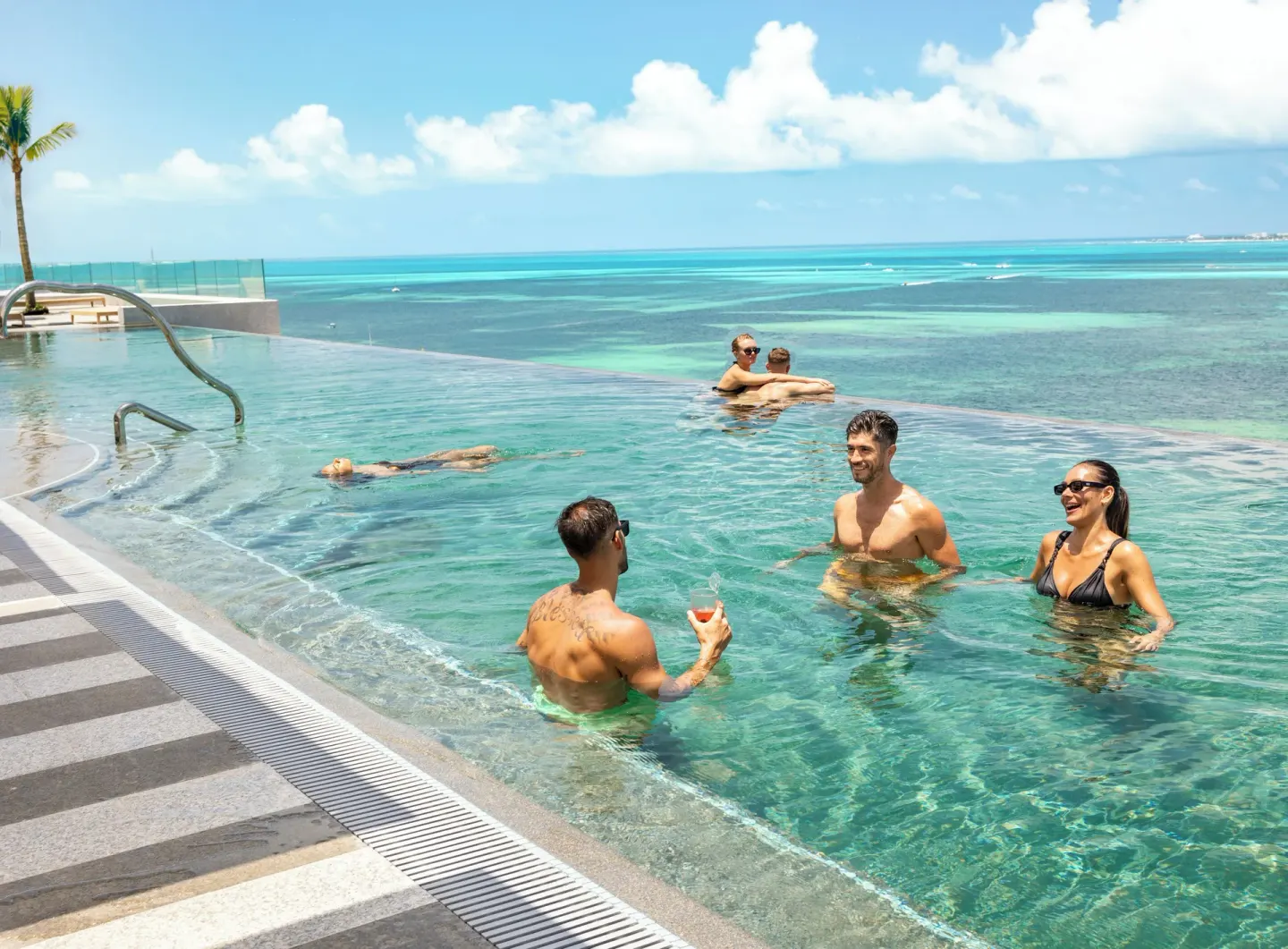 Guests relaxing in an infinity pool with Caribbean views at Hotel Mousai Cancun.