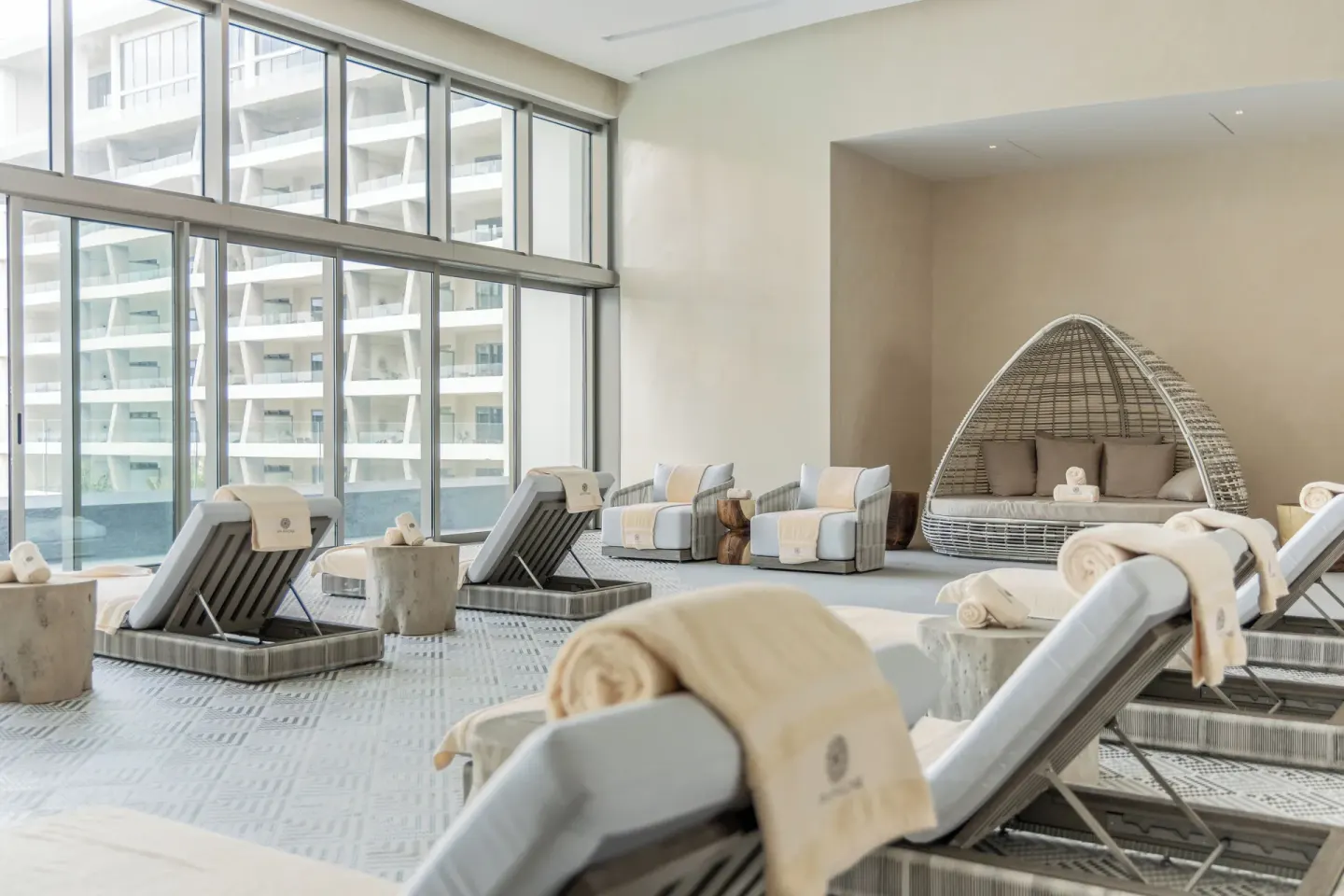 Spa relaxation lounge with loungers and a woven daybed at Hotel Mousai Cancun.