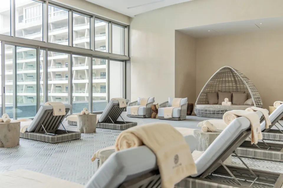 Spa relaxation lounge with loungers and a woven daybed at Hotel Mousai Cancun.