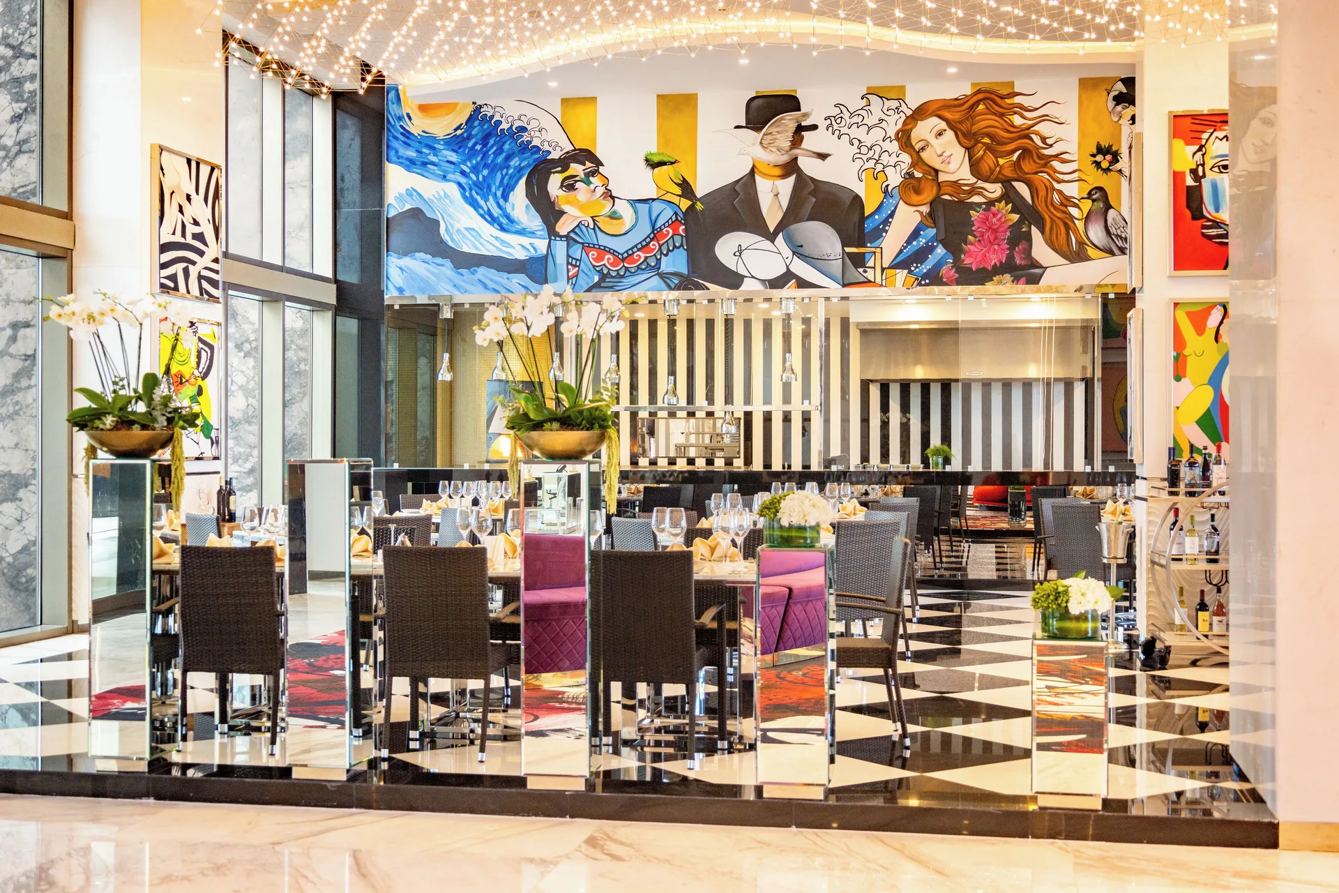 Dining room with colorful murals and set tables at Hotel Mousai Cancun.