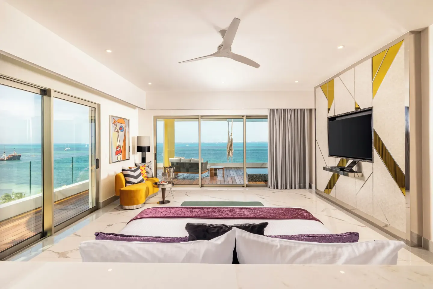 Corner Suite Ocean Front room with king bed, TV wall, and balcony at Hotel Mousai Cancun.
