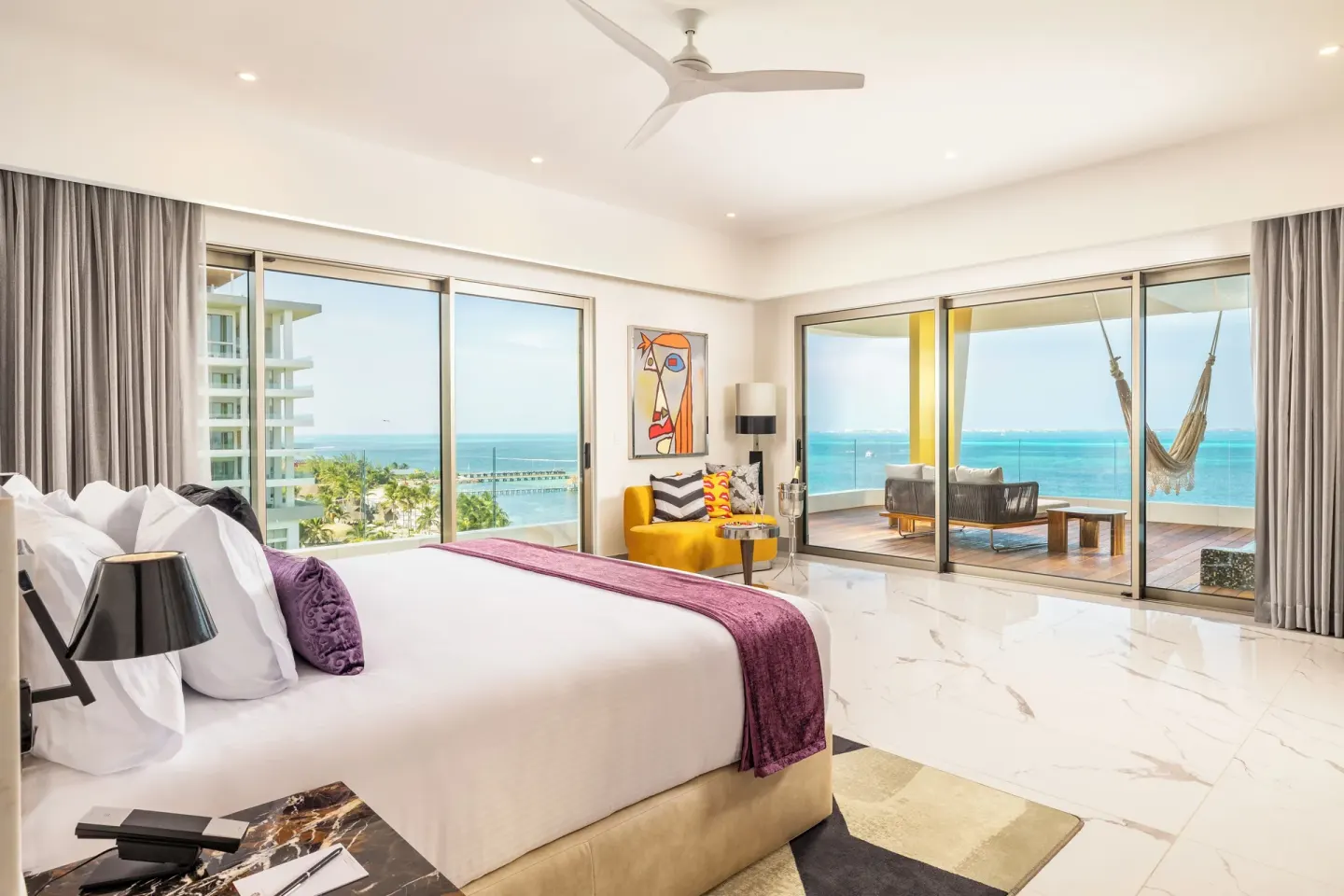 Corner Suite Ocean Front king bed with ocean-view windows at Hotel Mousai Cancun.