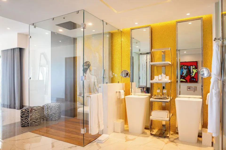 Suite Ocean Front bathroom with glass shower and gold wall at Hotel Mousai Cancun.