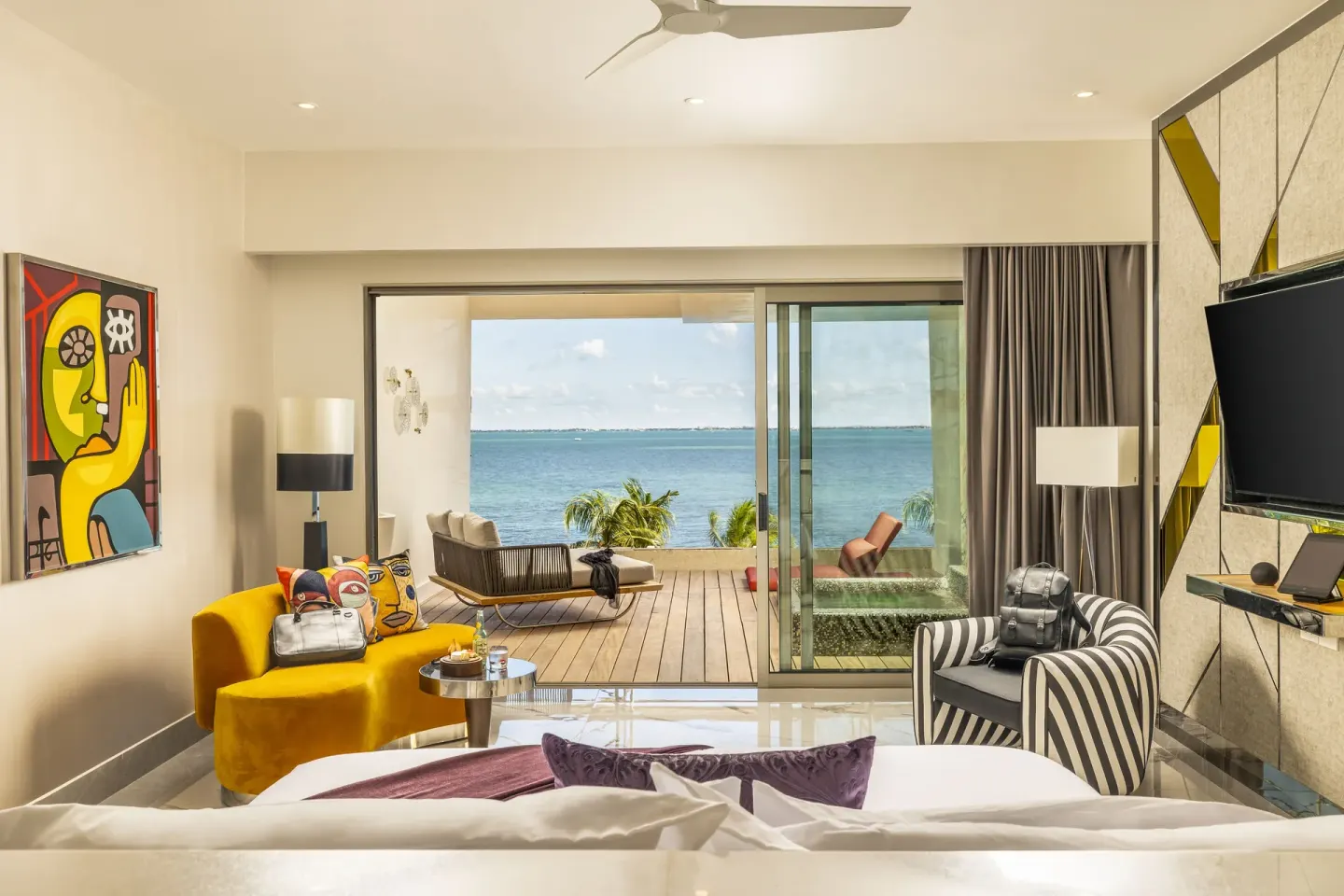 Suite ocean front bed facing balcony and turquoise water at Hotel Mousai Cancun.