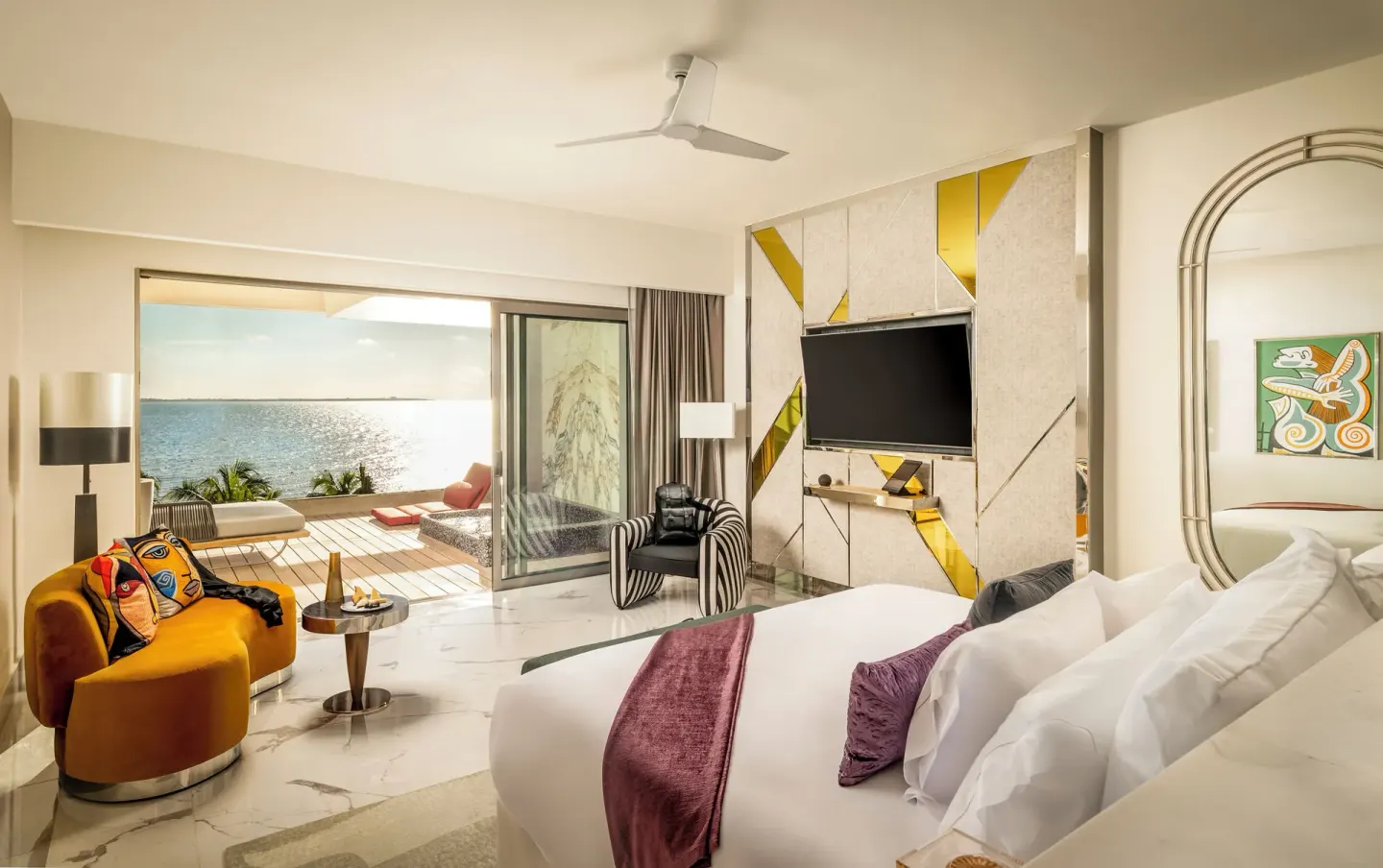 Suite ocean front king bed with seating area and terrace view at Hotel Mousai Cancun.