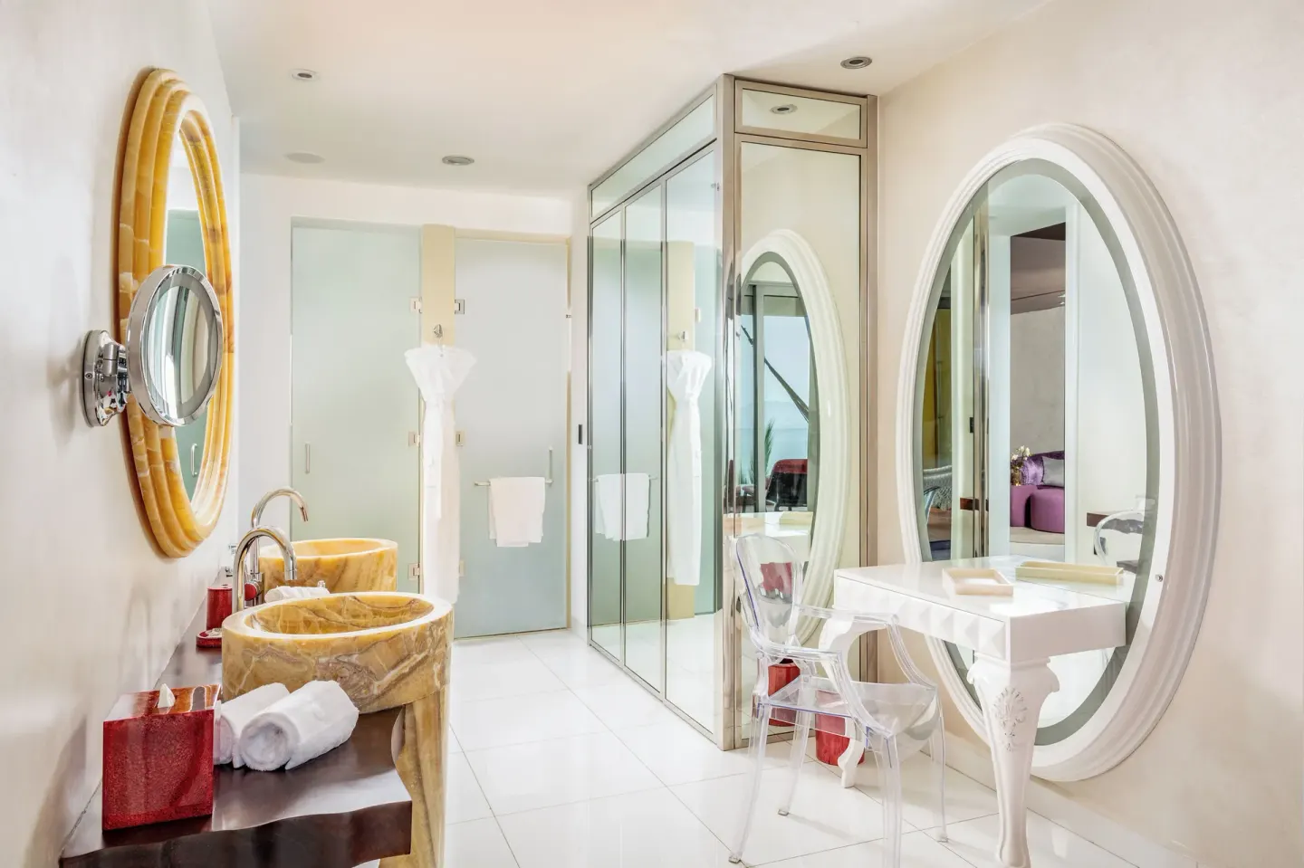 Bright bathroom with oval mirrors and glass shower at Hotel Mousai Puerto Vallarta.