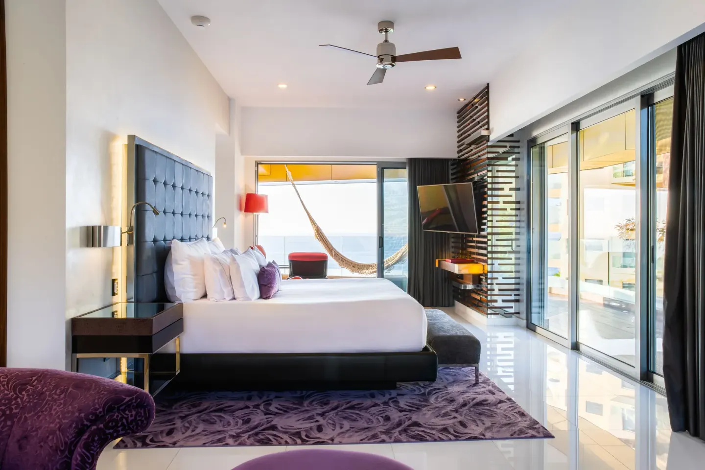 King bed guest room with balcony doors and ocean beyond at Hotel Mousai Puerto Vallarta.