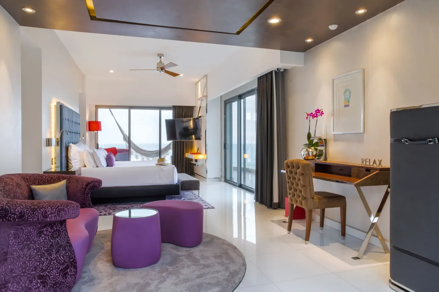 Suite seating area with king bed, desk, and balcony doors at Hotel Mousai Puerto Vallarta.