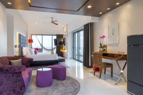 Suite seating area with king bed, desk, and balcony doors at Hotel Mousai Puerto Vallarta.