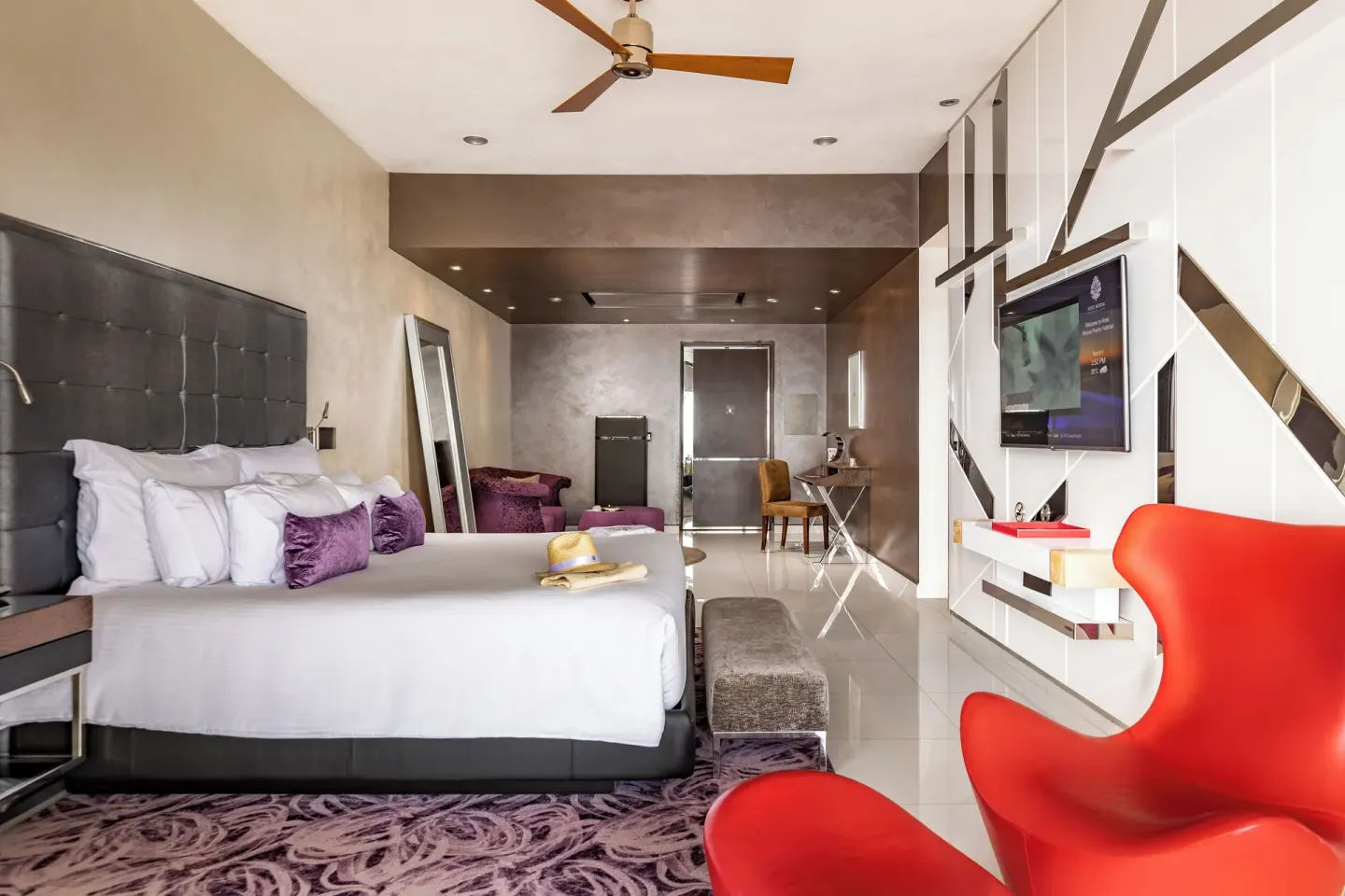King bed guest room with red lounge chair and desk at Hotel Mousai Puerto Vallarta.