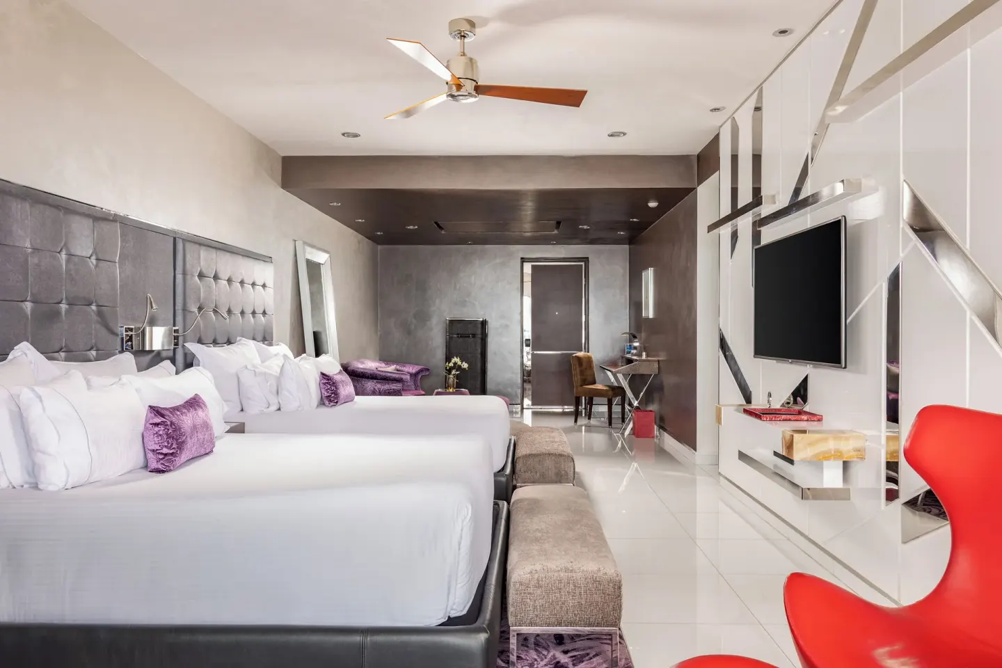 Two-bed guest room with gray headboards and red chair at Hotel Mousai Puerto Vallarta.