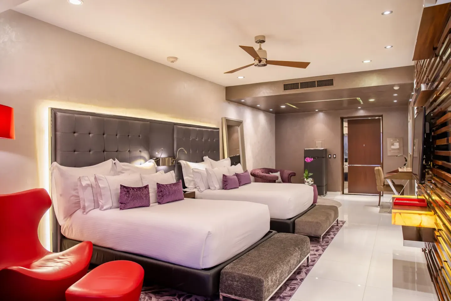 Double bed guest room with red chair and purple accents at Hotel Mousai Puerto Vallarta.