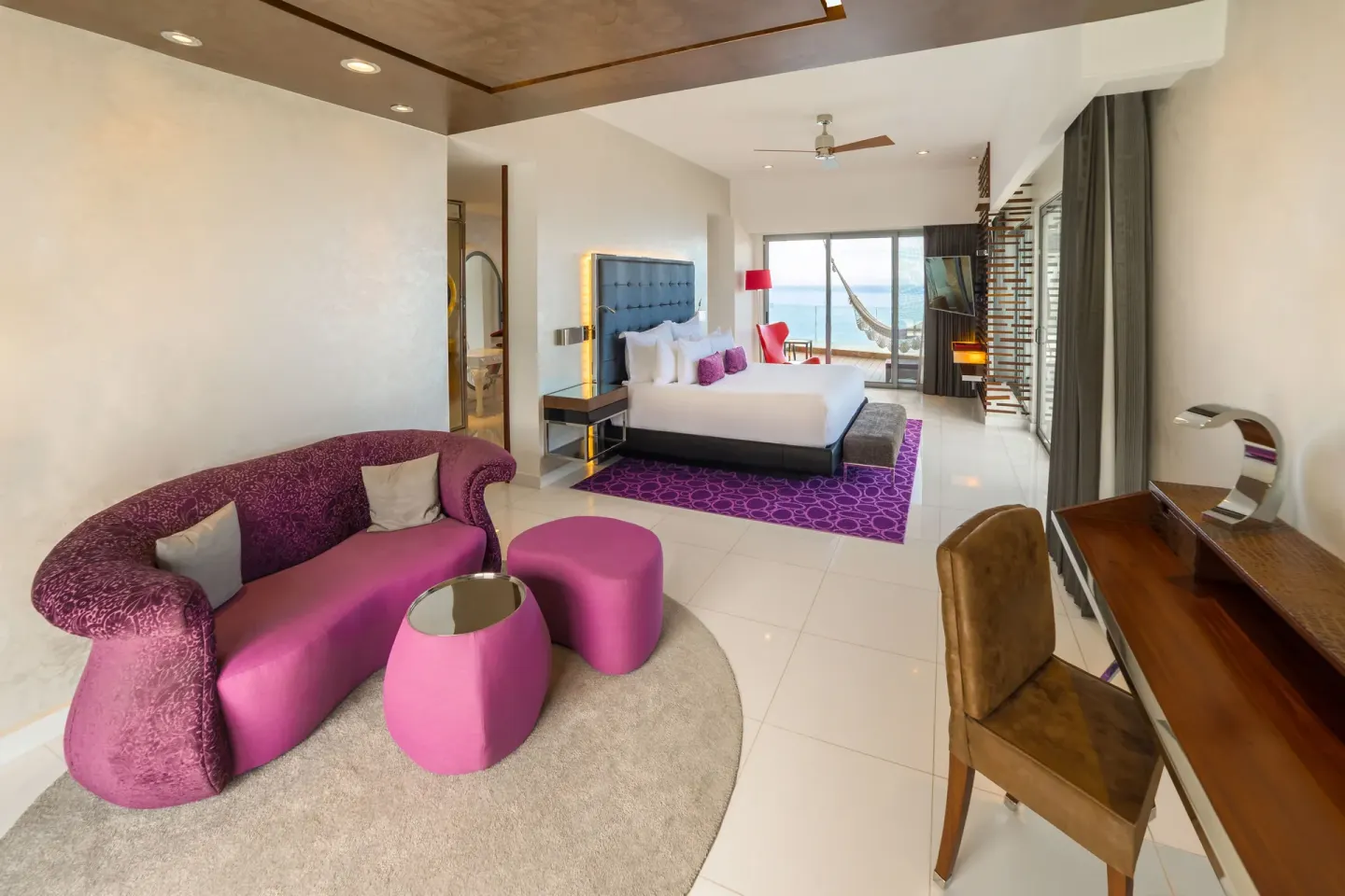 King bed suite with purple sofa and ocean-facing balcony at Hotel Mousai Puerto Vallarta.