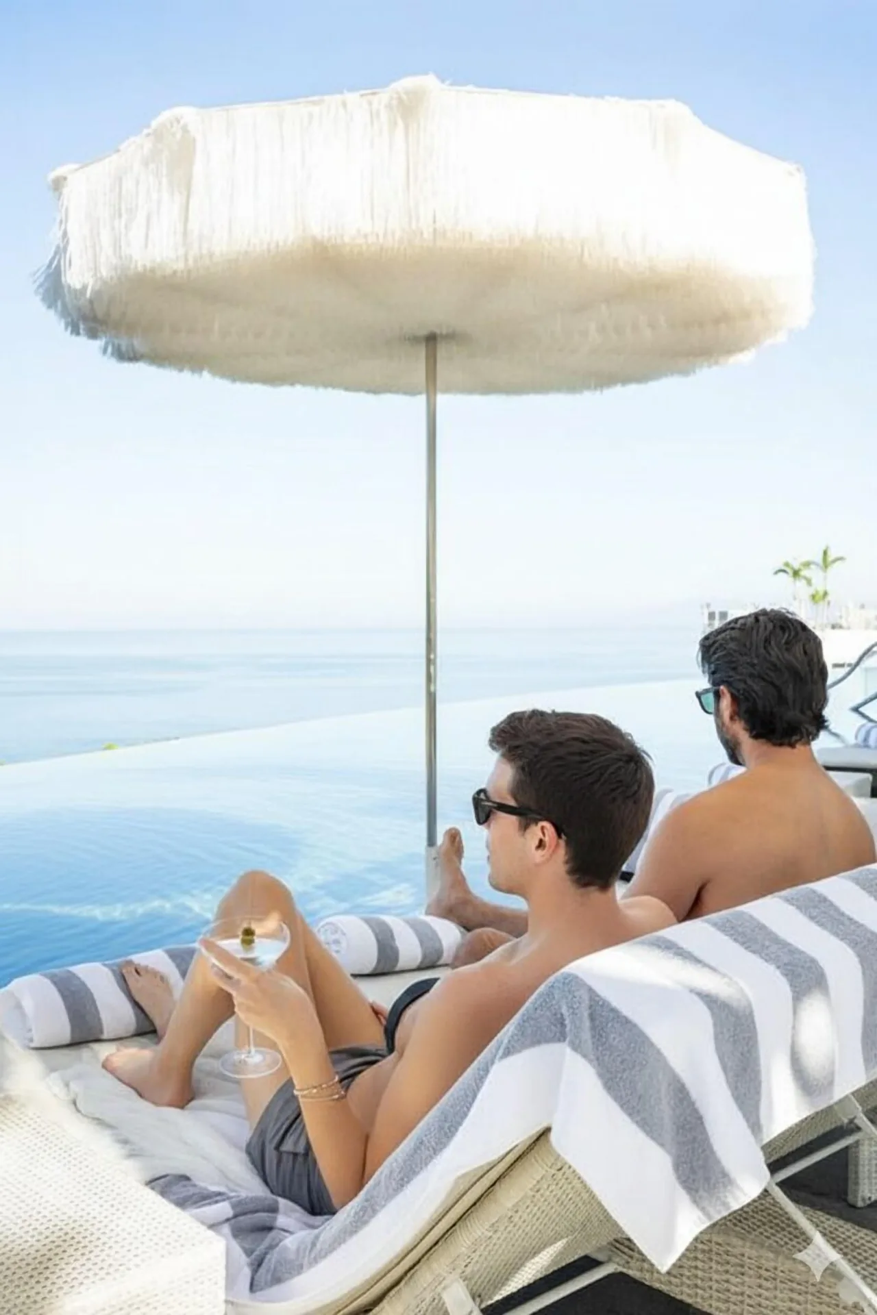 Guests lounge by an infinity pool with ocean views at Hotel Mousai Puerto Vallarta.
