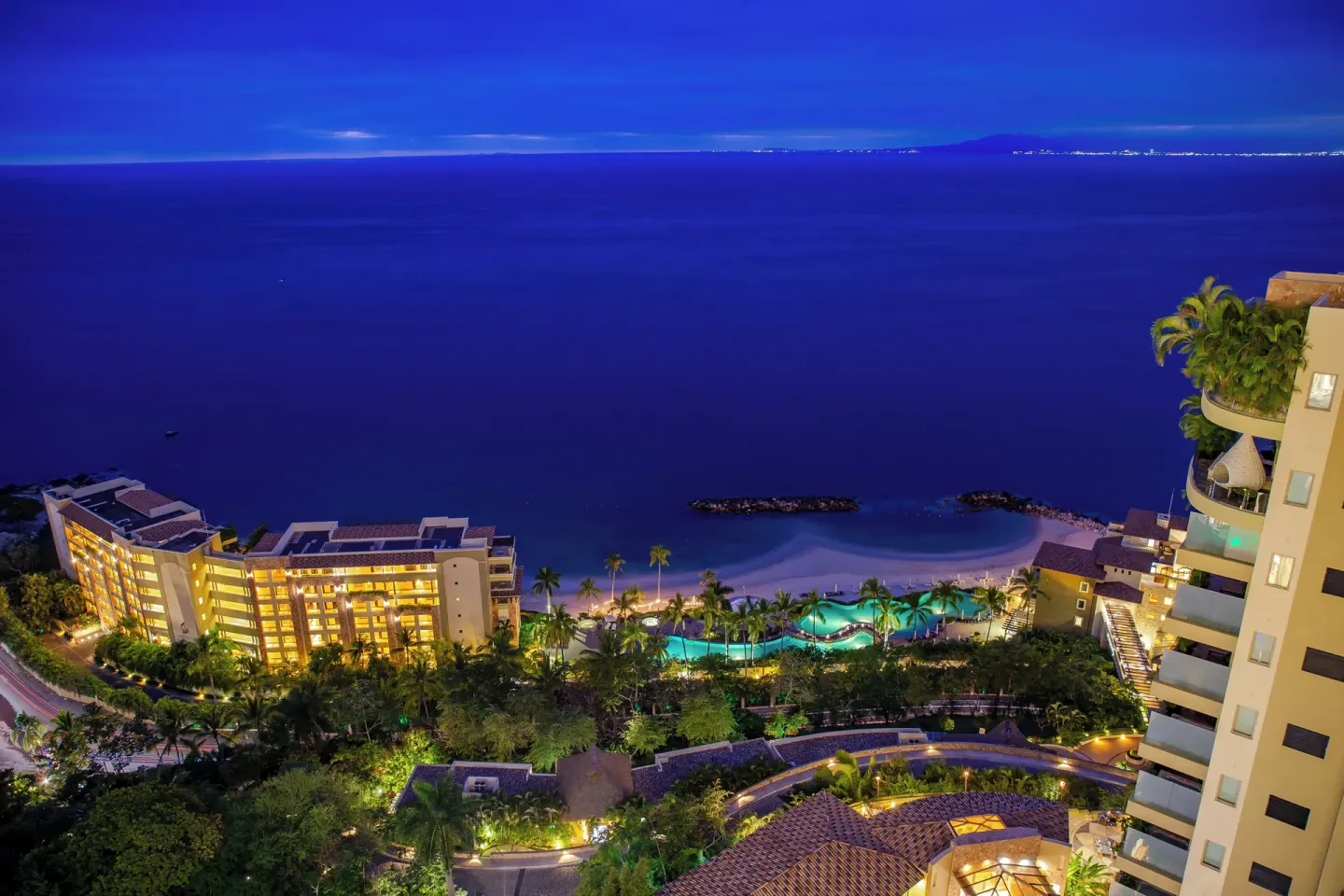 Night view of the beach, pool, and ocean from Hotel Mousai Puerto Vallarta.