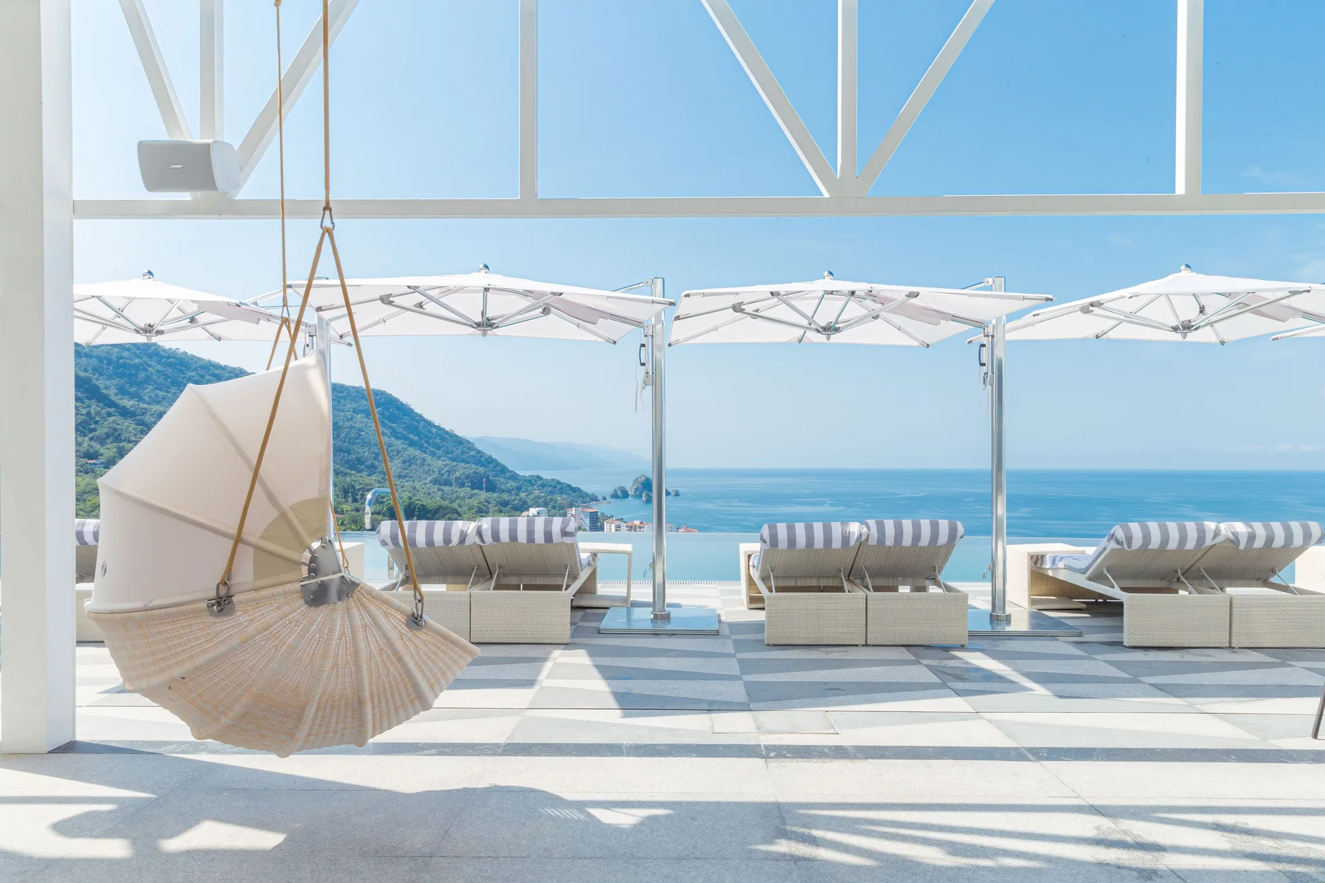 Hanging chair and ocean-view loungers at Hotel Mousai Puerto Vallarta.