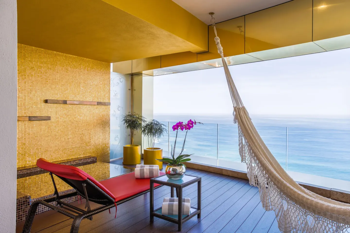 Terrace with hammock, red lounger, and ocean view at Hotel Mousai Puerto Vallarta.