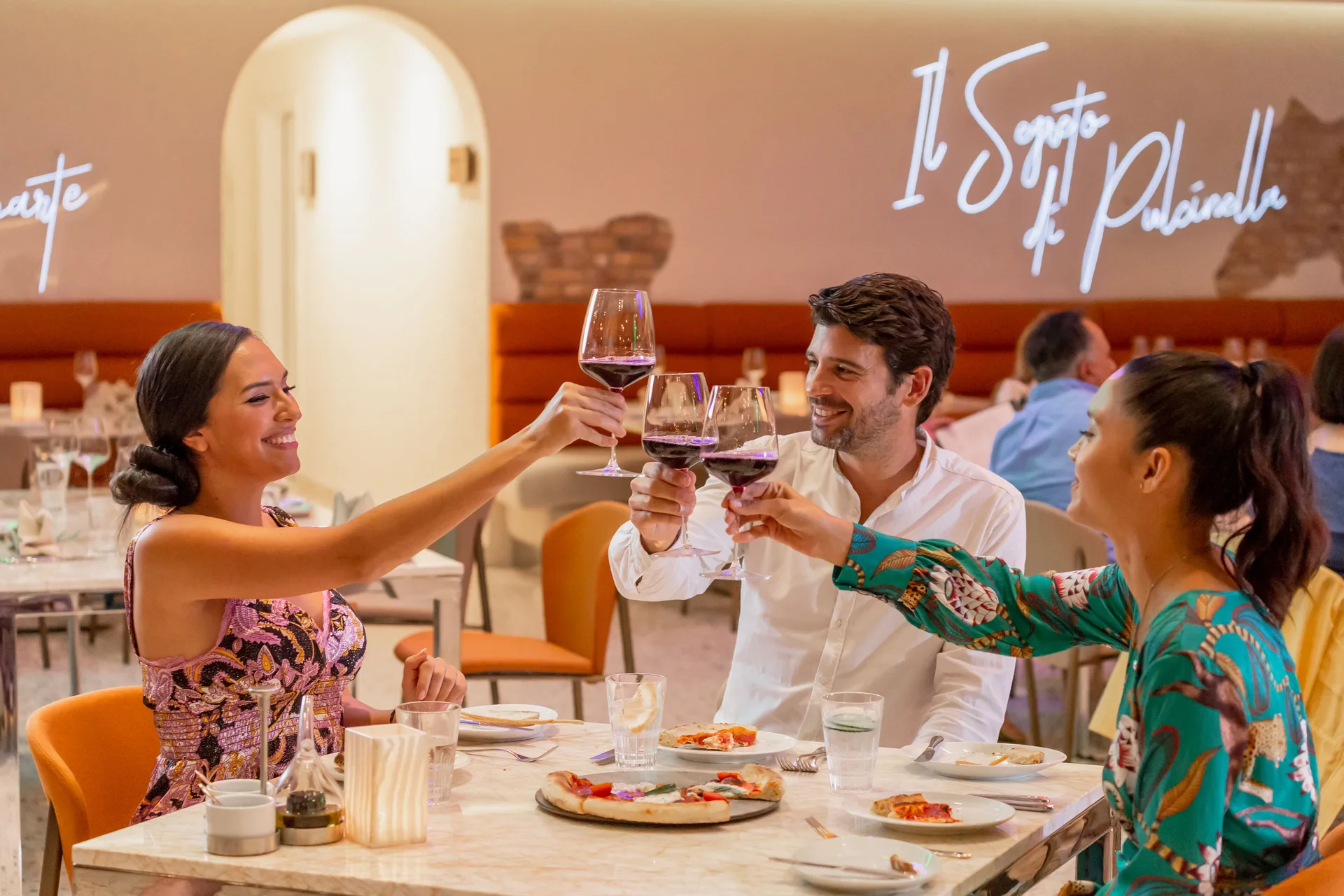 Guests toast wine over pizza in NOI restaurant at Hotel Mousai Puerto Vallarta.