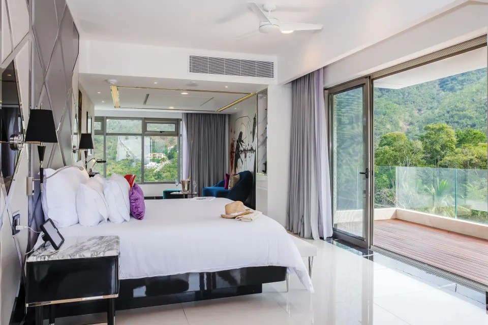 Corner Suite king bed beside sliding balcony doors at Hotel Mousai Puerto Vallarta.