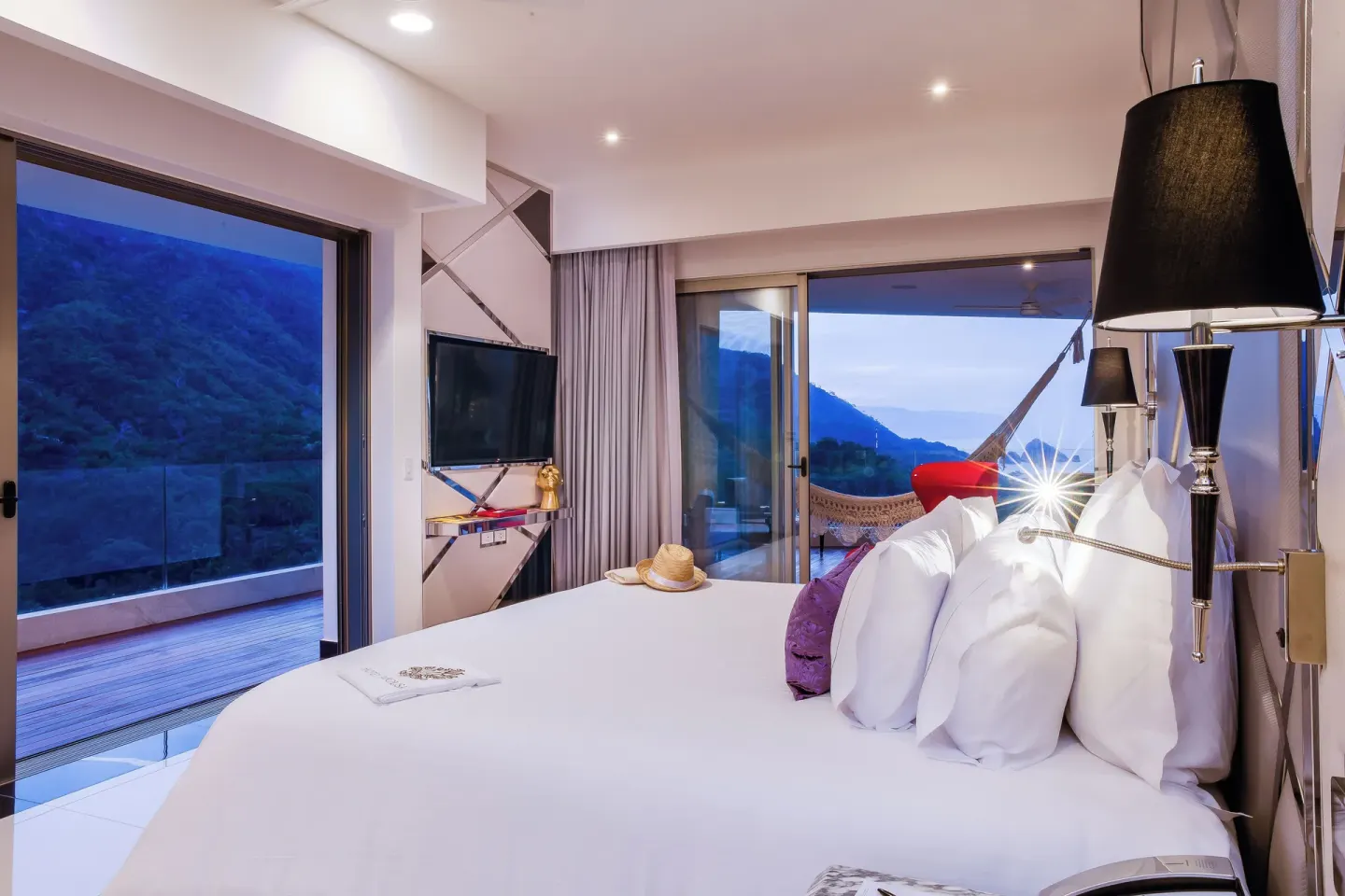 Evening view of a Corner Suite king bed and balcony at Hotel Mousai Puerto Vallarta.
