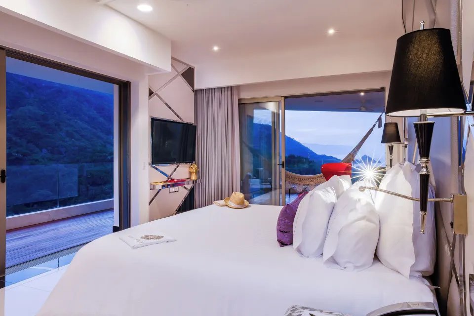Evening view of a Corner Suite king bed and balcony at Hotel Mousai Puerto Vallarta.