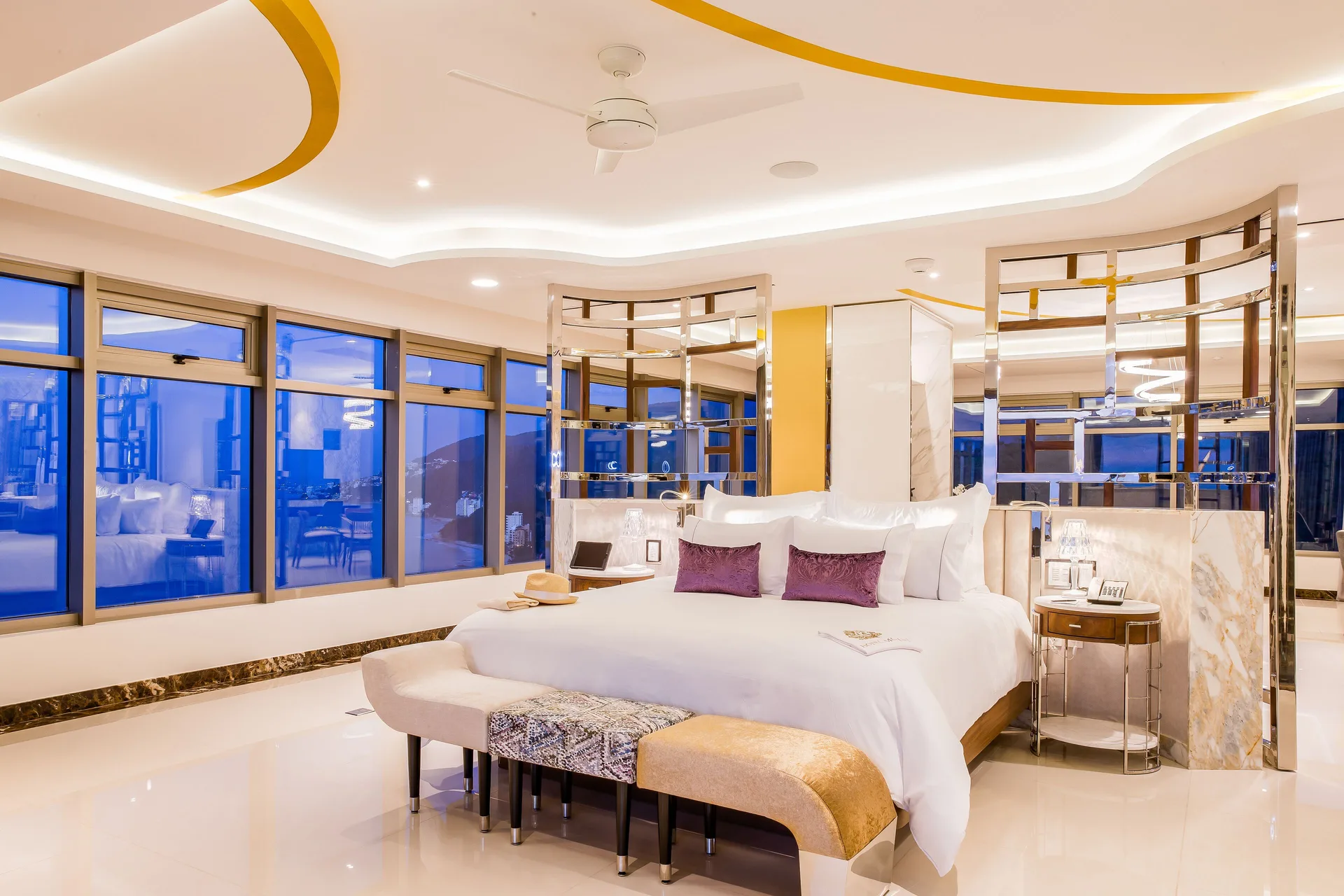 Master Suite king bed with mirrored panels and blue evening windows at Hotel Mousai Puerto Vallarta.